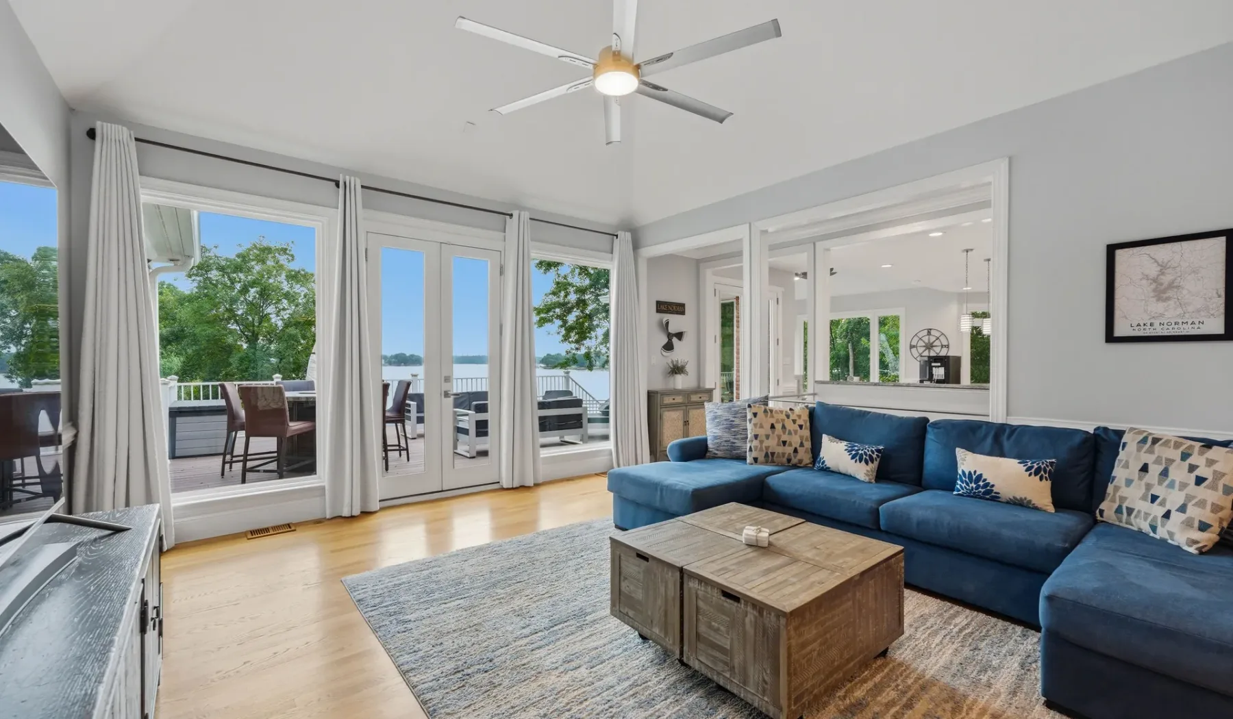 A bright living room with blue seating and glass doors opening to a deck.