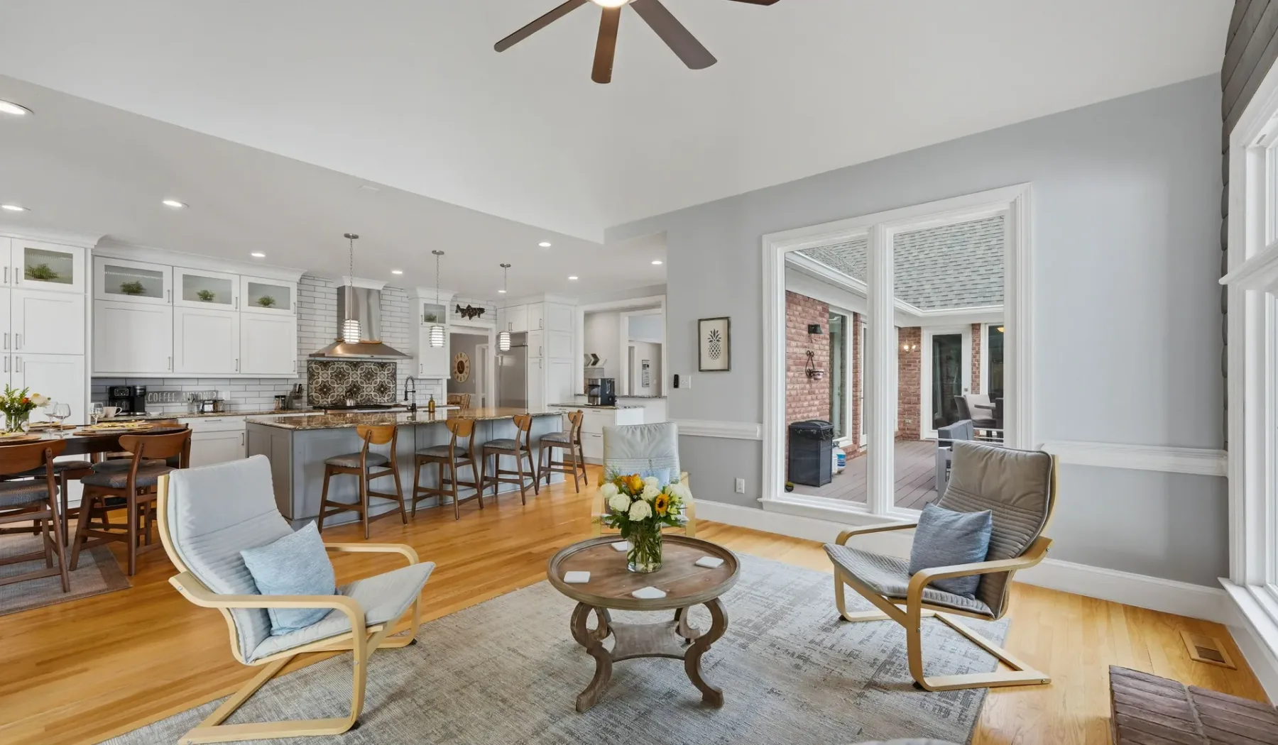 An open-plan living and kitchen area has seating beside a dining island.