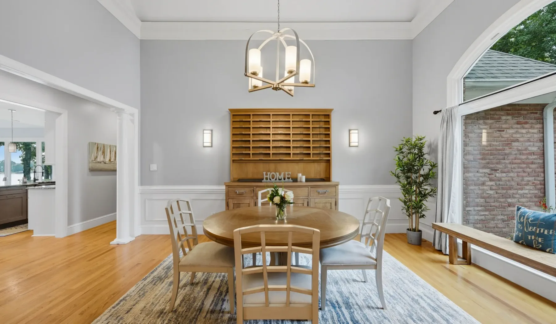 A dining room with a round table and chairs beneath a hanging light.
