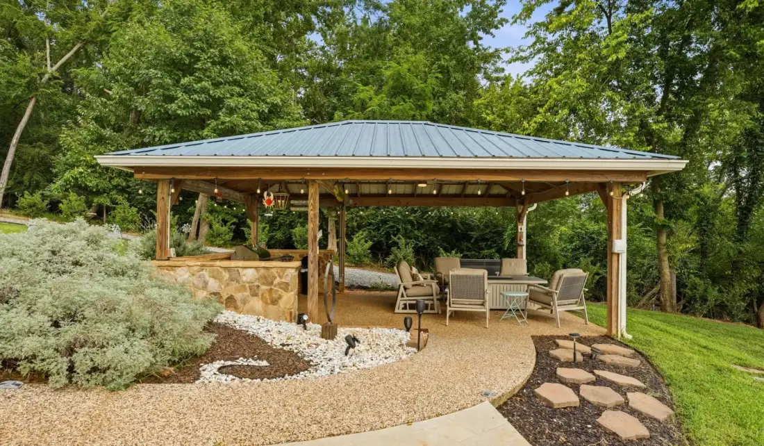 An open-sided pavilion with seating overlooks a landscaped garden.