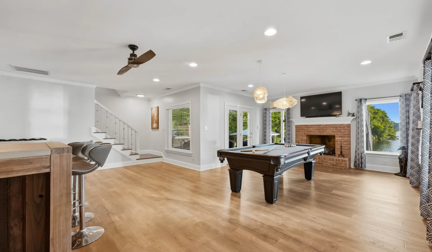 A bright recreation room features a pool table and a bar counter.