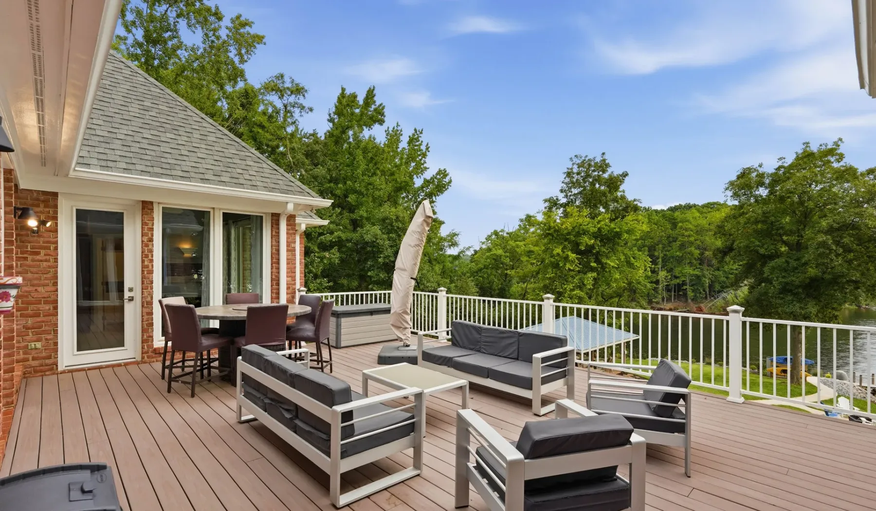 An outdoor deck with seating overlooks a pool and surrounding trees.