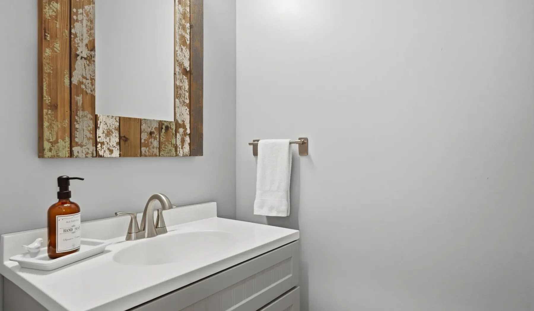 A bathroom vanity with a white sink, mirror, and towel.