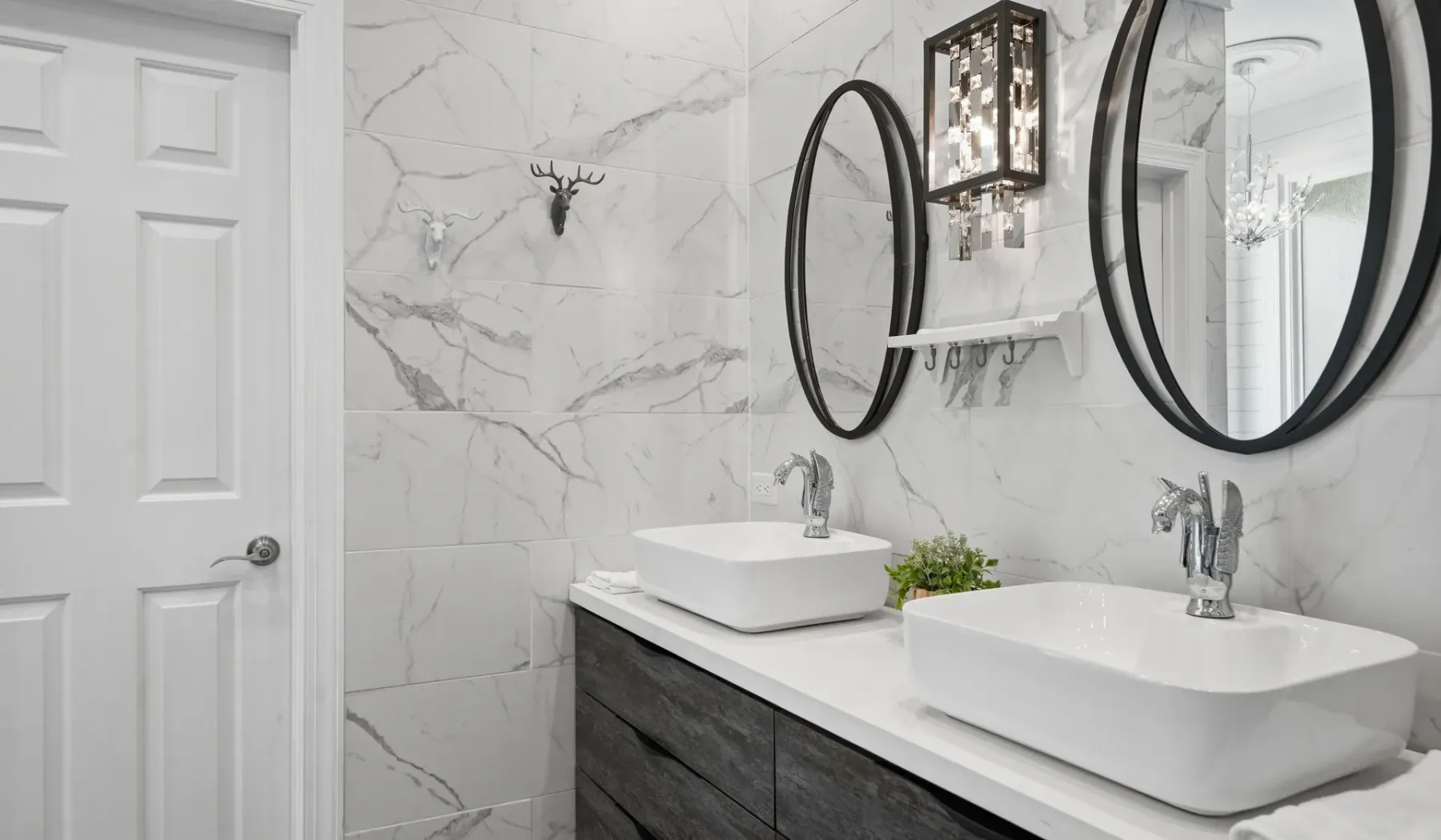 A bathroom vanity with two white vessel sinks and round mirrors.