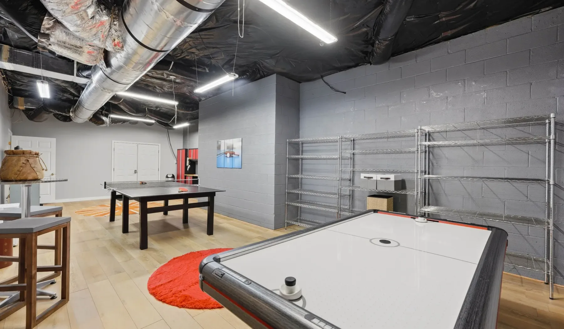 A recreation room with an air hockey table and shelving along the wall.