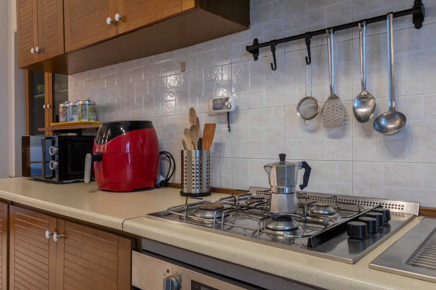 A kitchen counter with a stovetop, coffee maker, and red appliance.