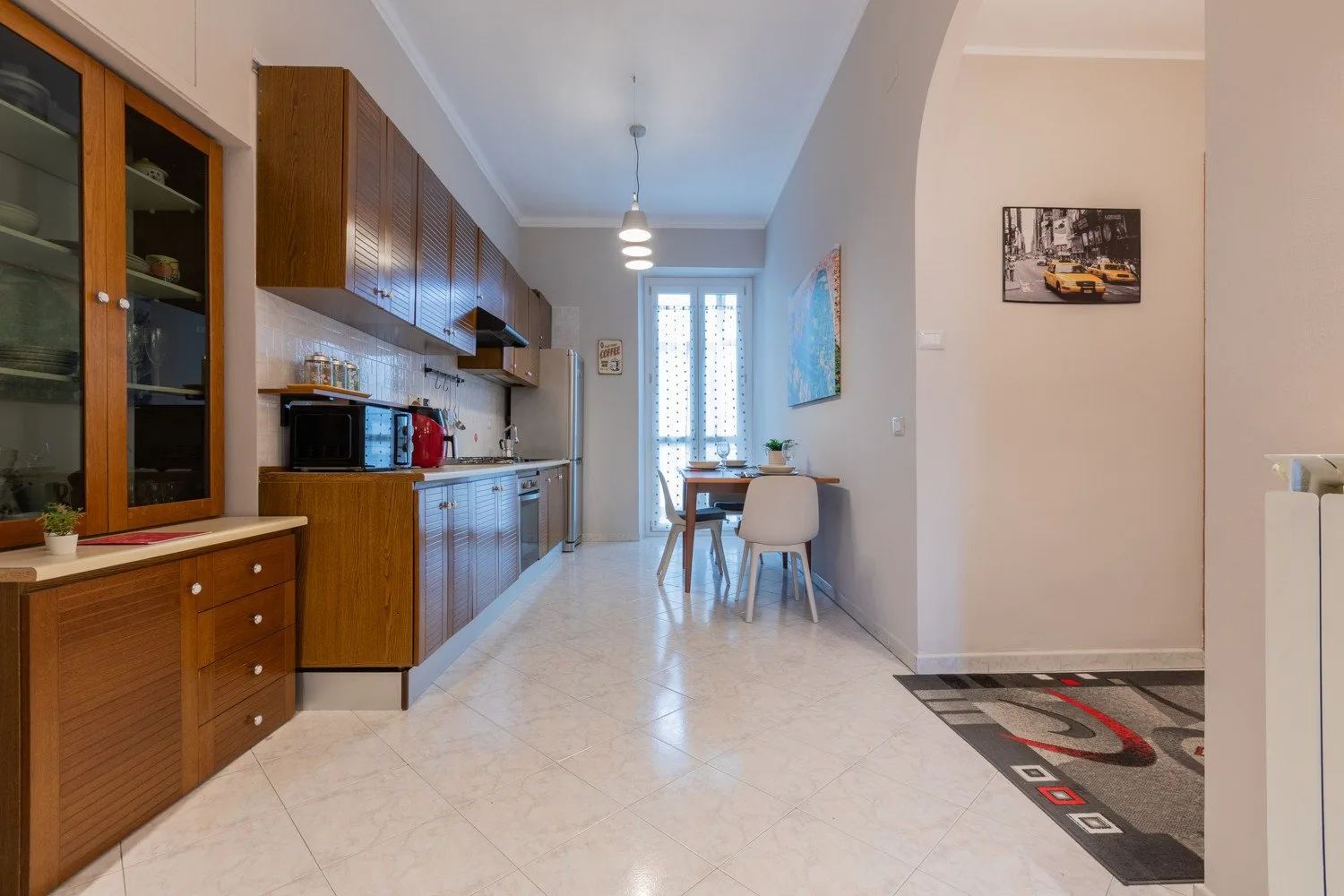 A narrow kitchen and dining area with wooden cabinets and a table by the window.