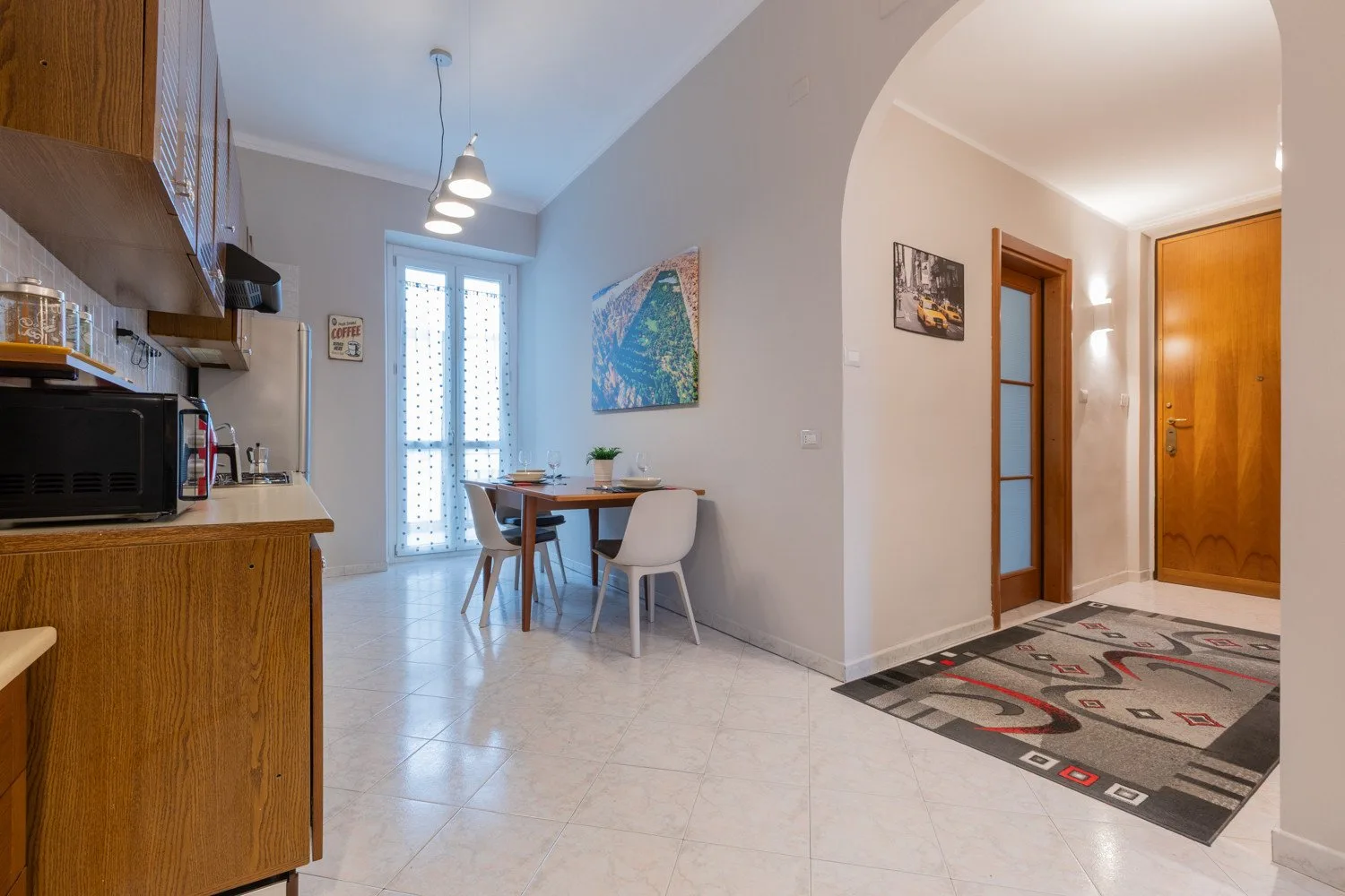 A dining area beside a kitchen opens onto a hallway with wooden doors.