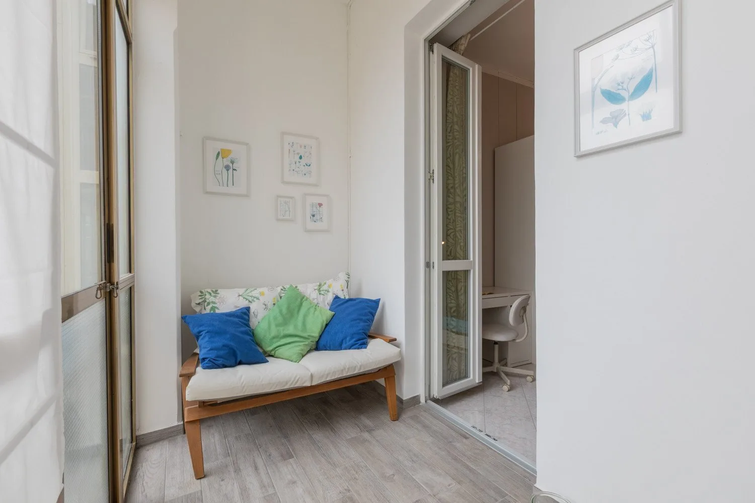 A small sitting area with a cushioned bench beneath framed artwork.