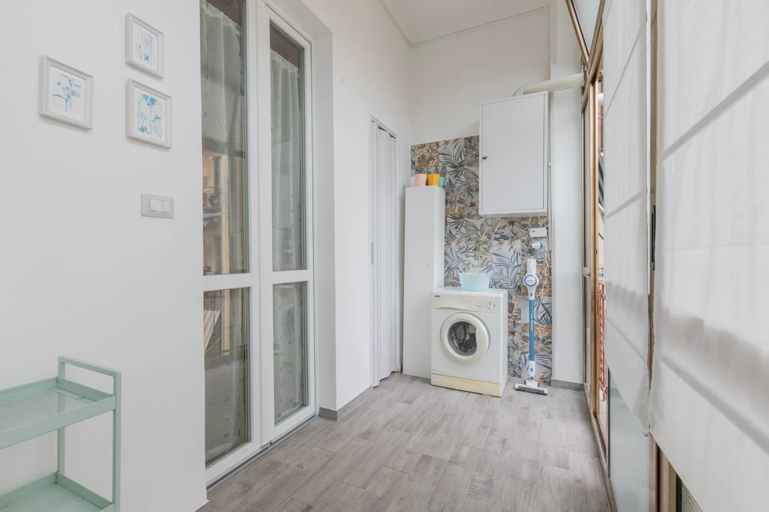 A bright laundry area with a washing machine and patterned tile wall.