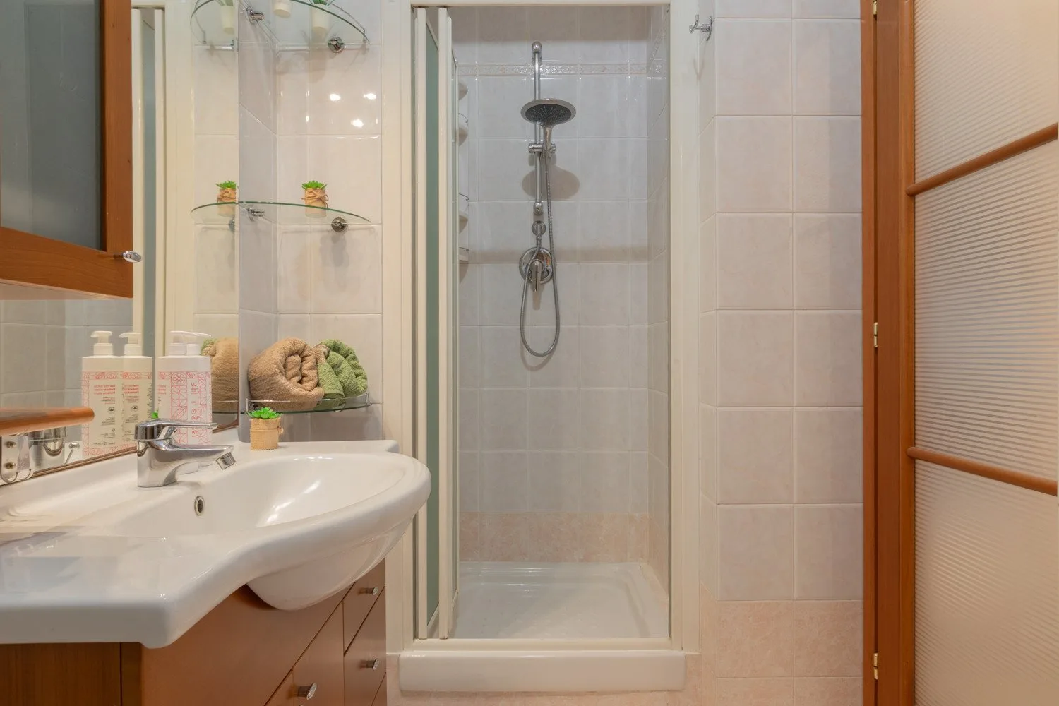 A tiled bathroom with a sink and a glass-enclosed shower.