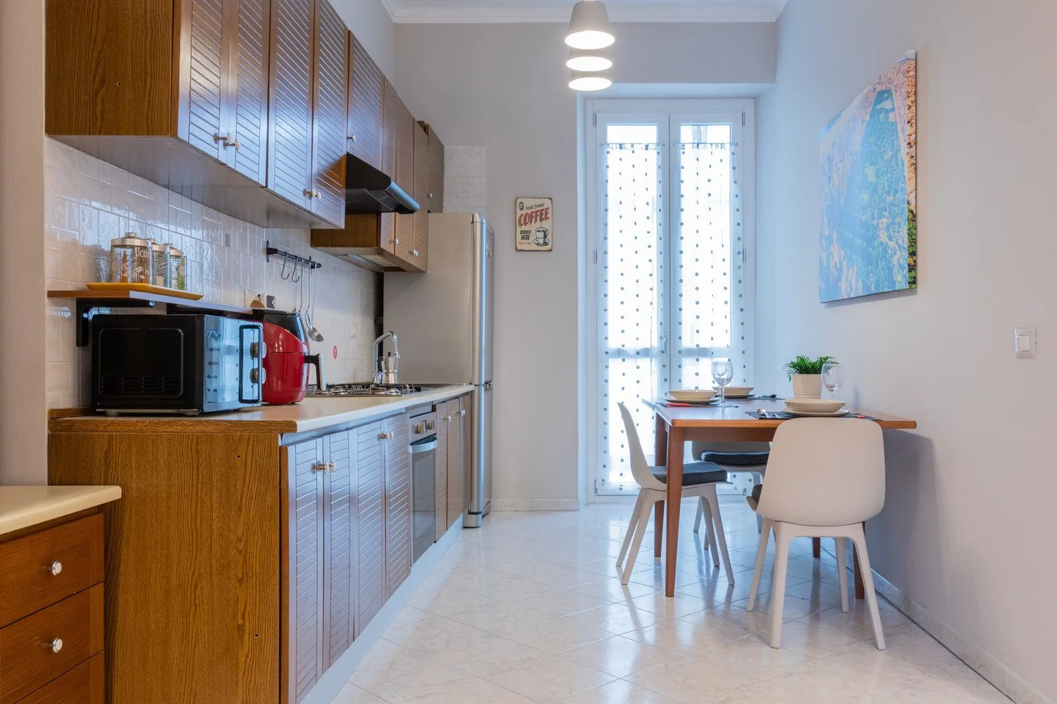 A kitchen and dining area with wooden cabinets and a table beside the windows.