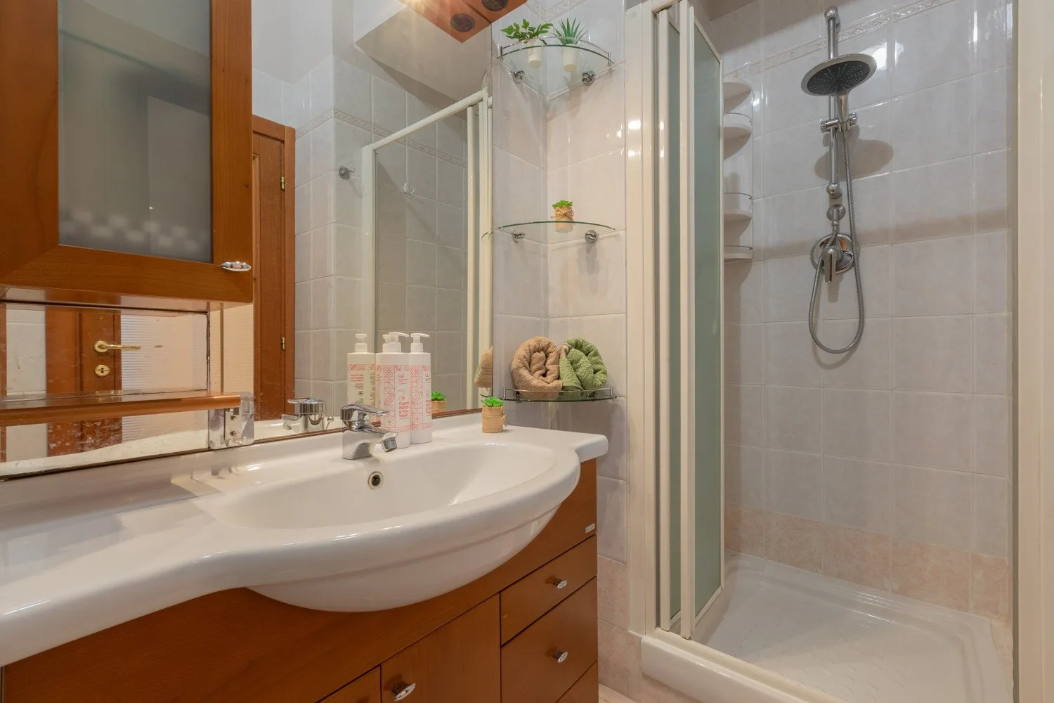A bathroom with a sink, mirror, and glass-enclosed shower.