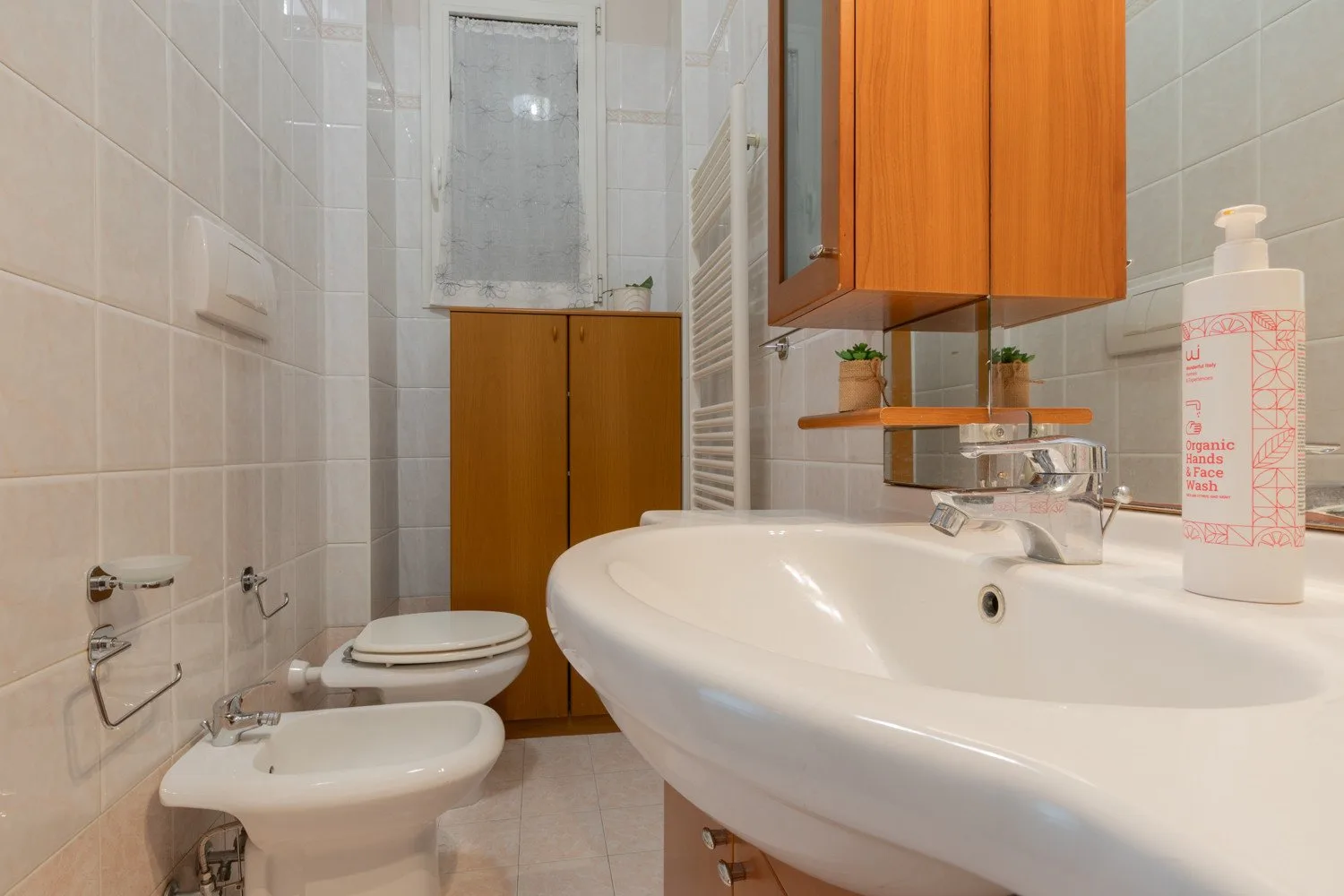 A tiled bathroom with a large sink, toilet, and bidet.