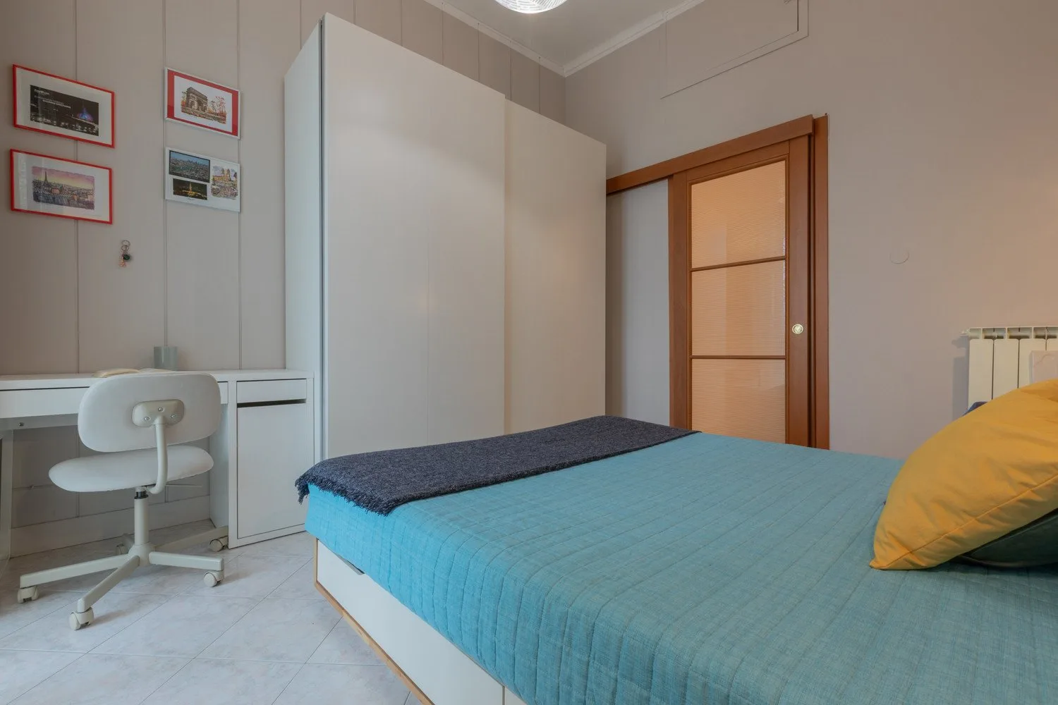 A bedroom with a bed, a desk, and a wooden door.
