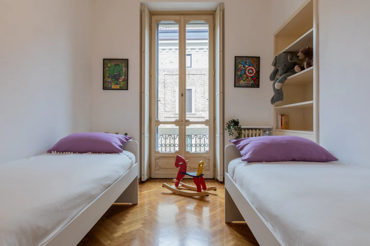 Un dormitorio con dos camas individuales y un juguete balancín de madera entre ellas.