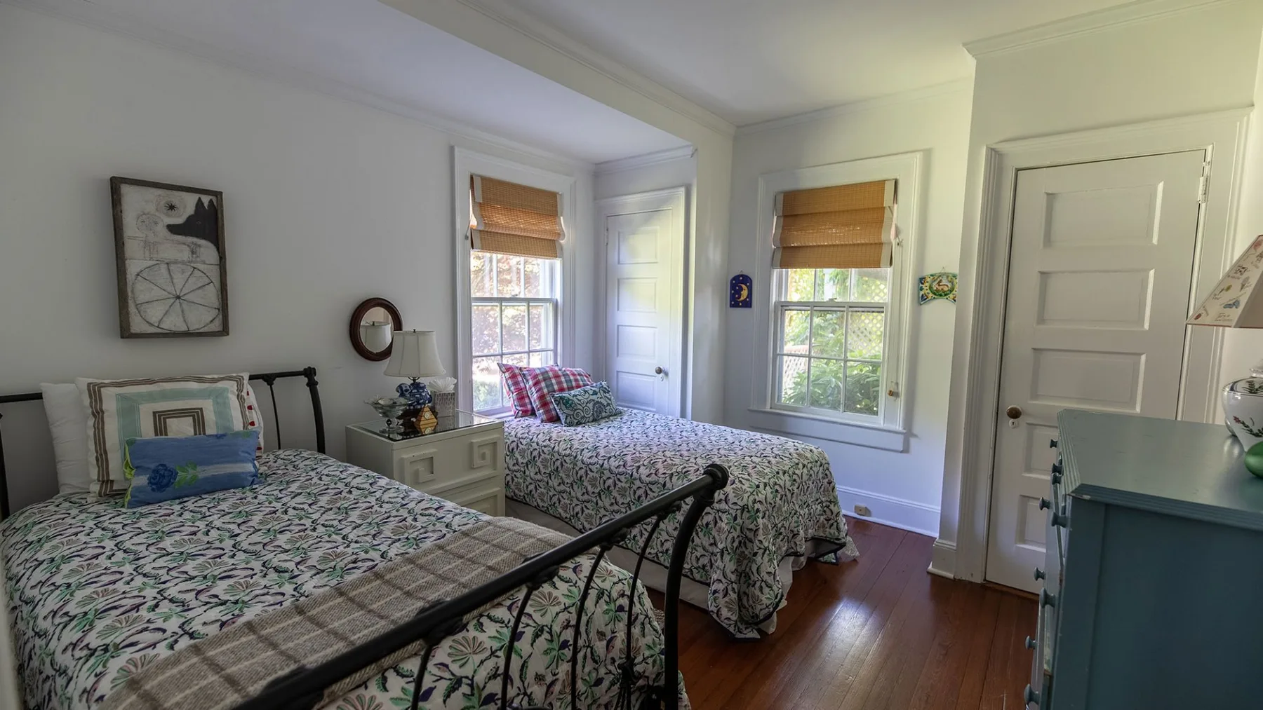 Un dormitorio con dos camas junto a ventanas con persianas parcialmente bajadas.