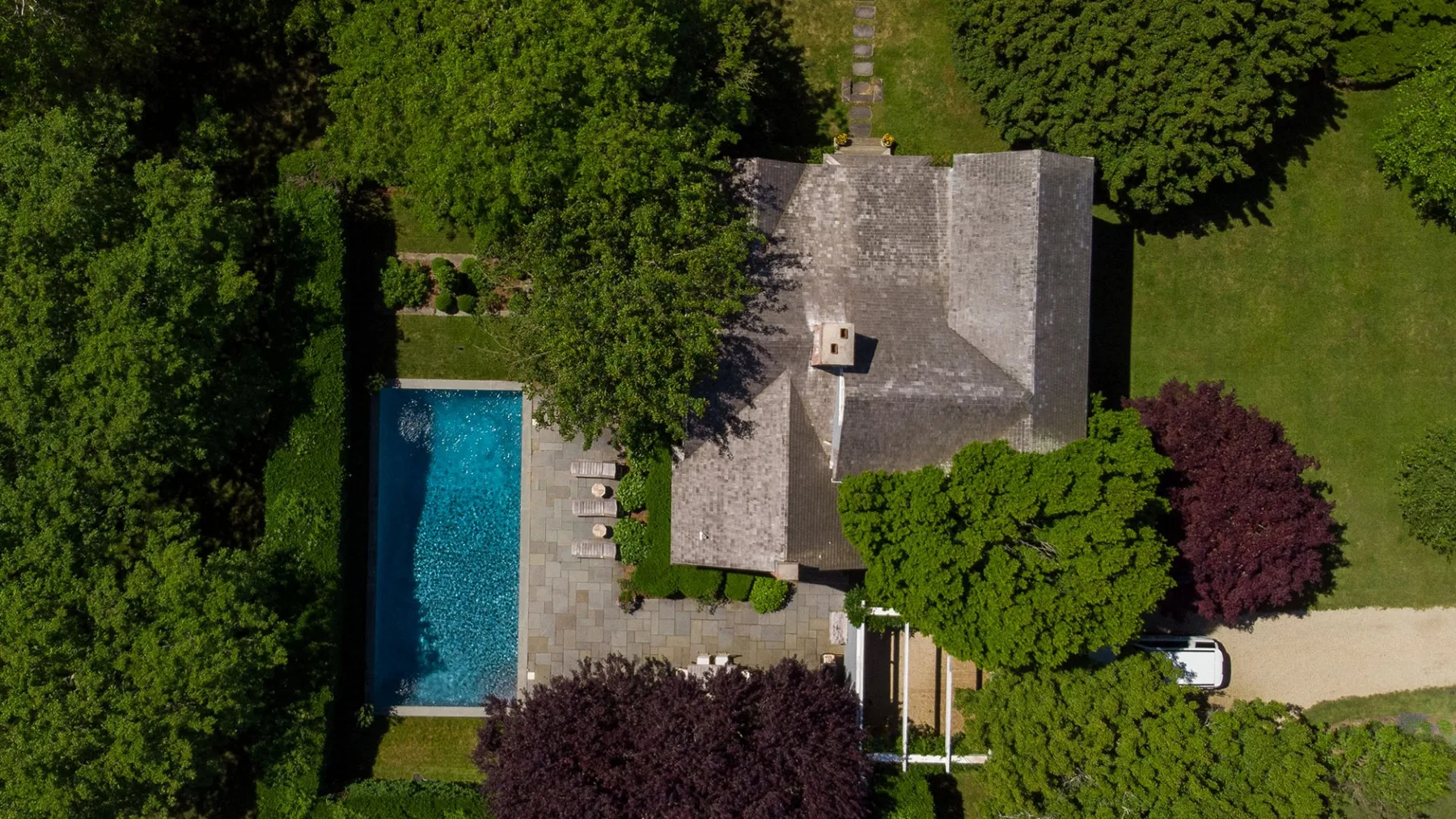 Una vista aérea muestra una casa, una piscina y árboles alrededor.