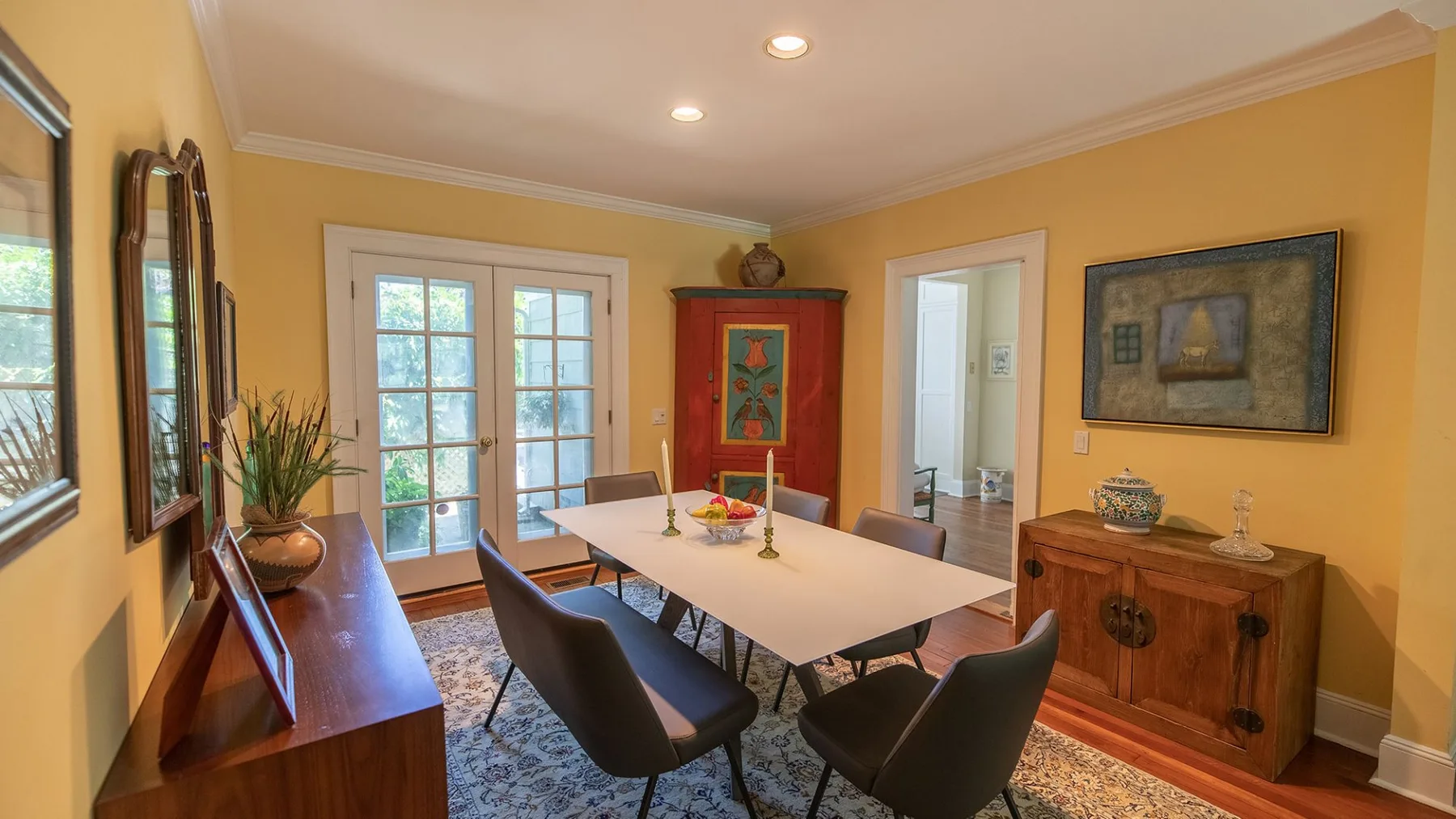 Un comedor con una mesa y sillas, cuadros enmarcados y un mueble de madera.