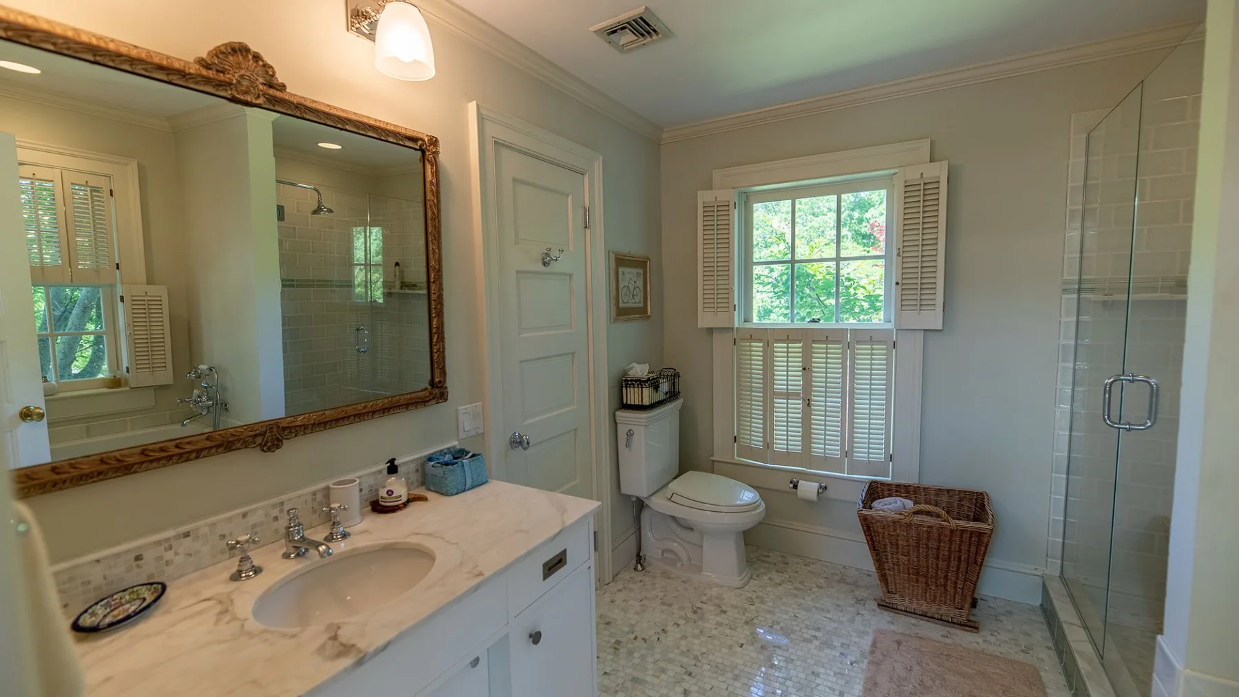 Un baño con tocador, inodoro, ventana y ducha de vidrio.