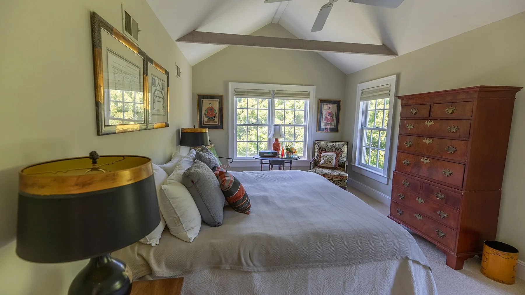Un dormitorio con una cama grande, ventanas y una cómoda de madera.