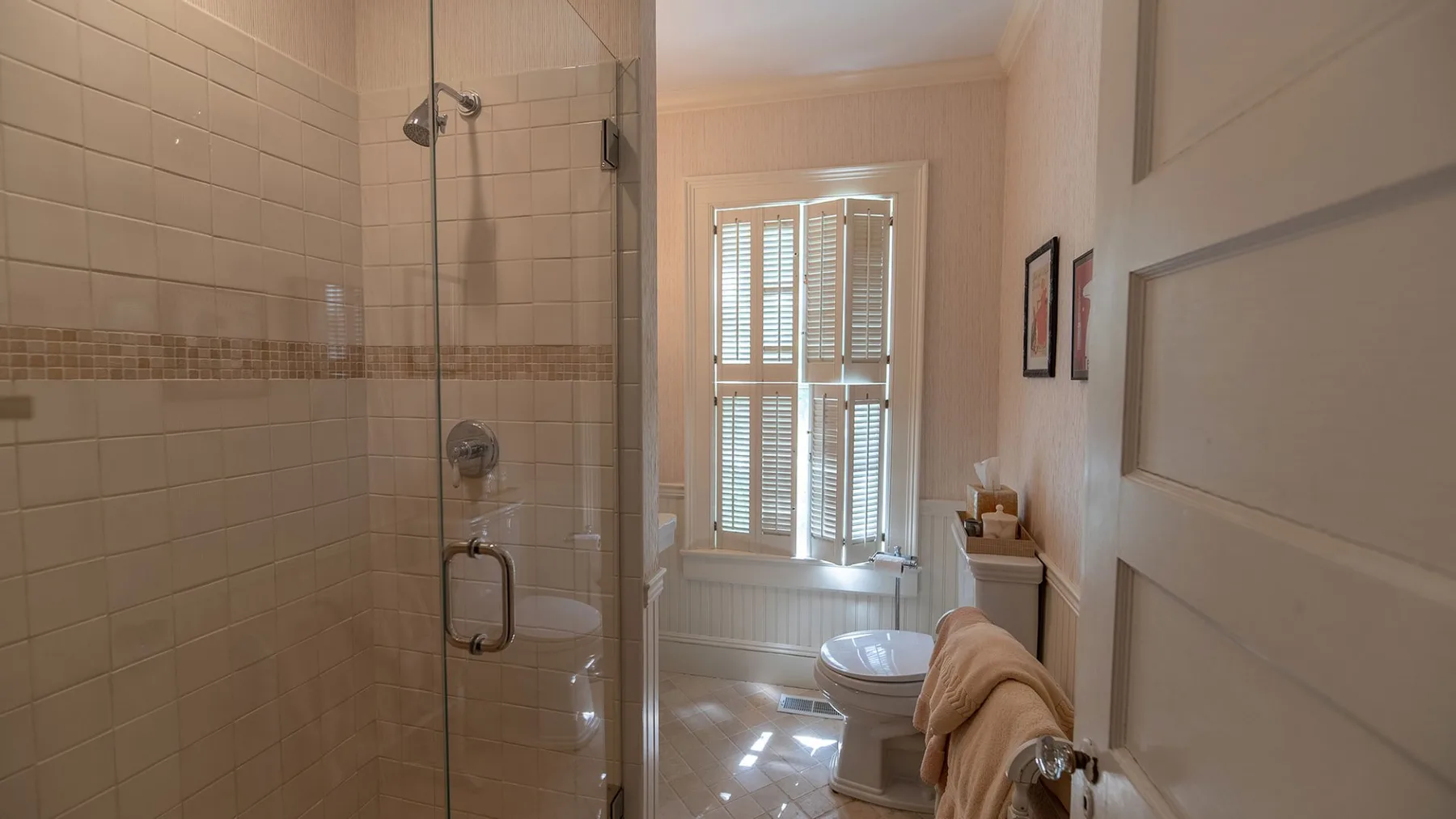 Un baño de azulejos con ducha, inodoro y ventana.