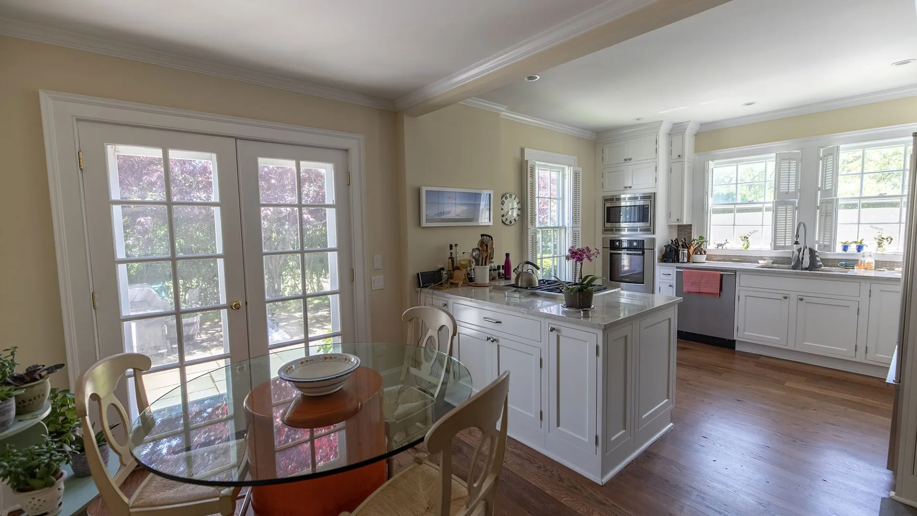 Una cocina luminosa con una isla central y puertas de vidrio junto a una mesa de comedor.