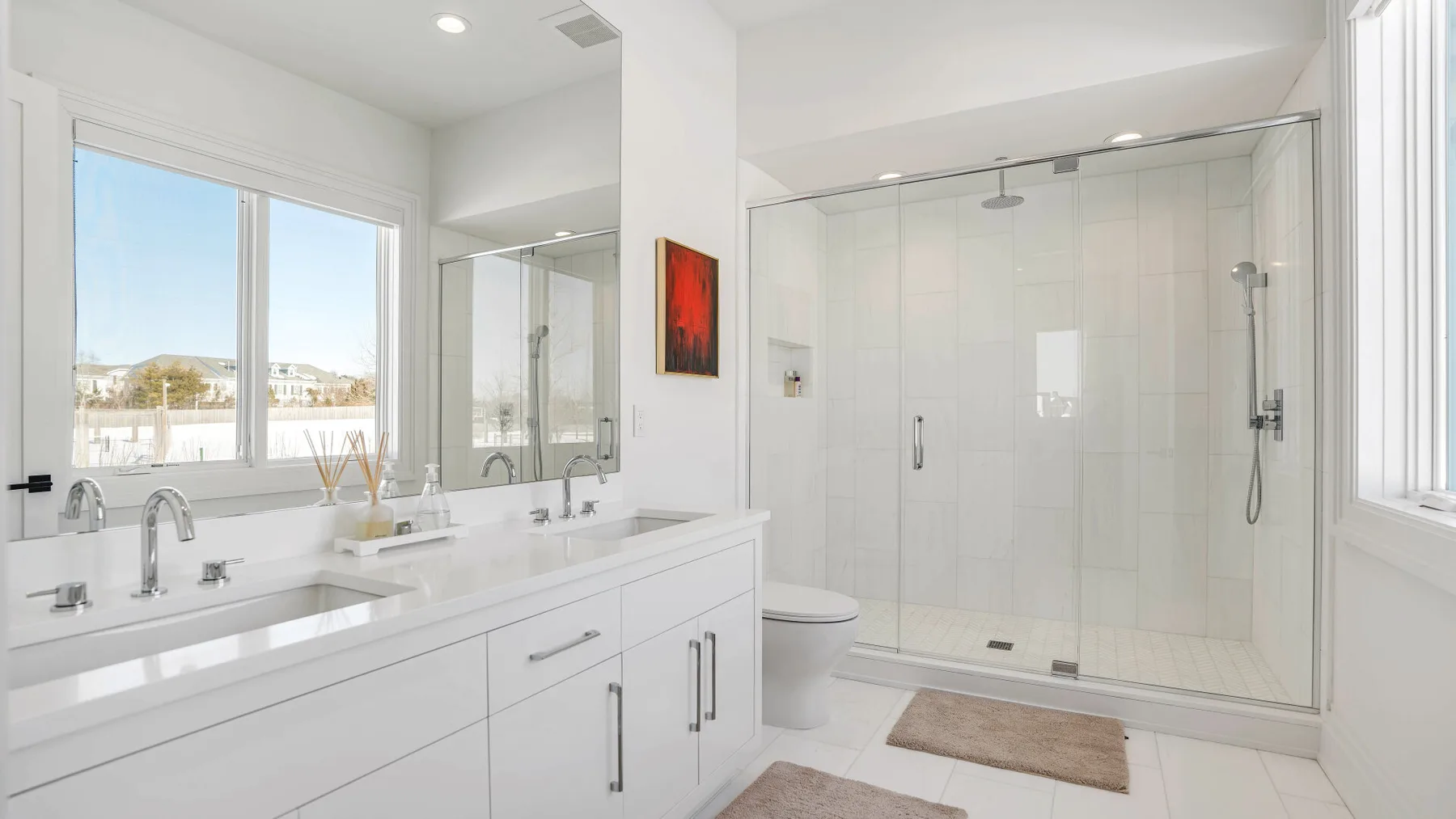 Un baño luminoso con un tocador blanco y una ducha de cristal.