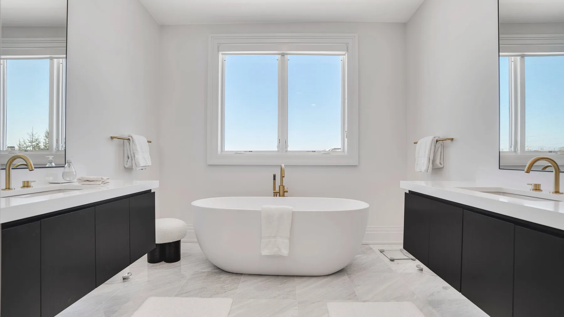 Un baño luminoso con una bañera exenta entre dos tocadores.