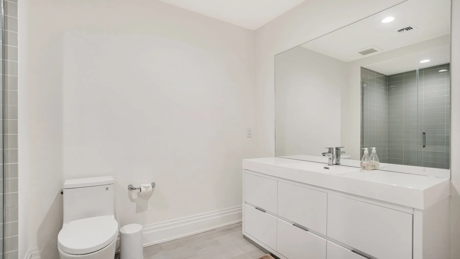 Un baño luminoso con un amplio tocador y un gran espejo de pared.