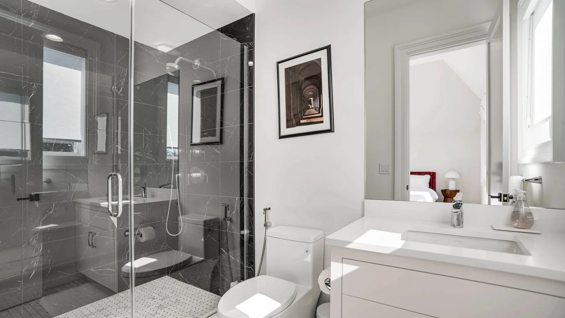 Un baño luminoso con una ducha de vidrio y un lavabo blanco.
