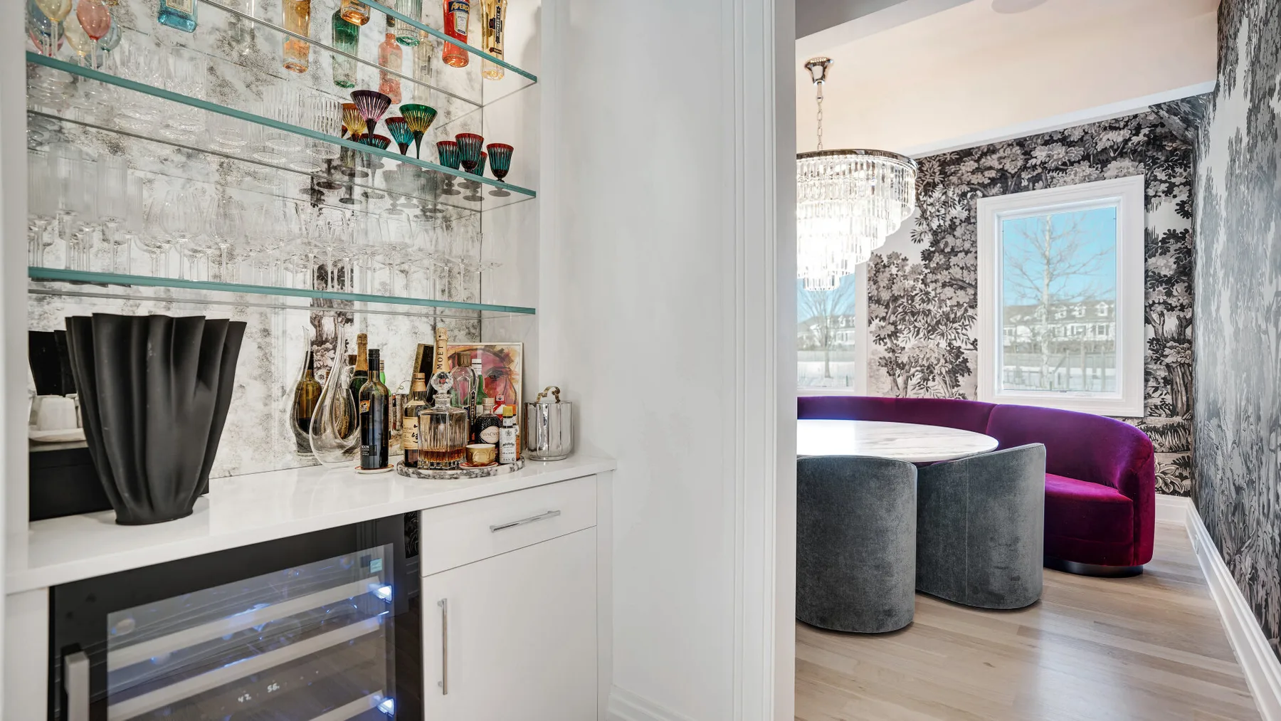 Una zona de bar empotrada con estantes de vidrio y un rincón para sentarse junto a las ventanas.