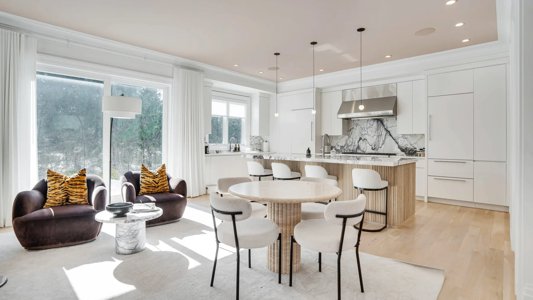 Una cocina y comedor diáfanos y luminosos, con una mesa redonda y grandes ventanales.