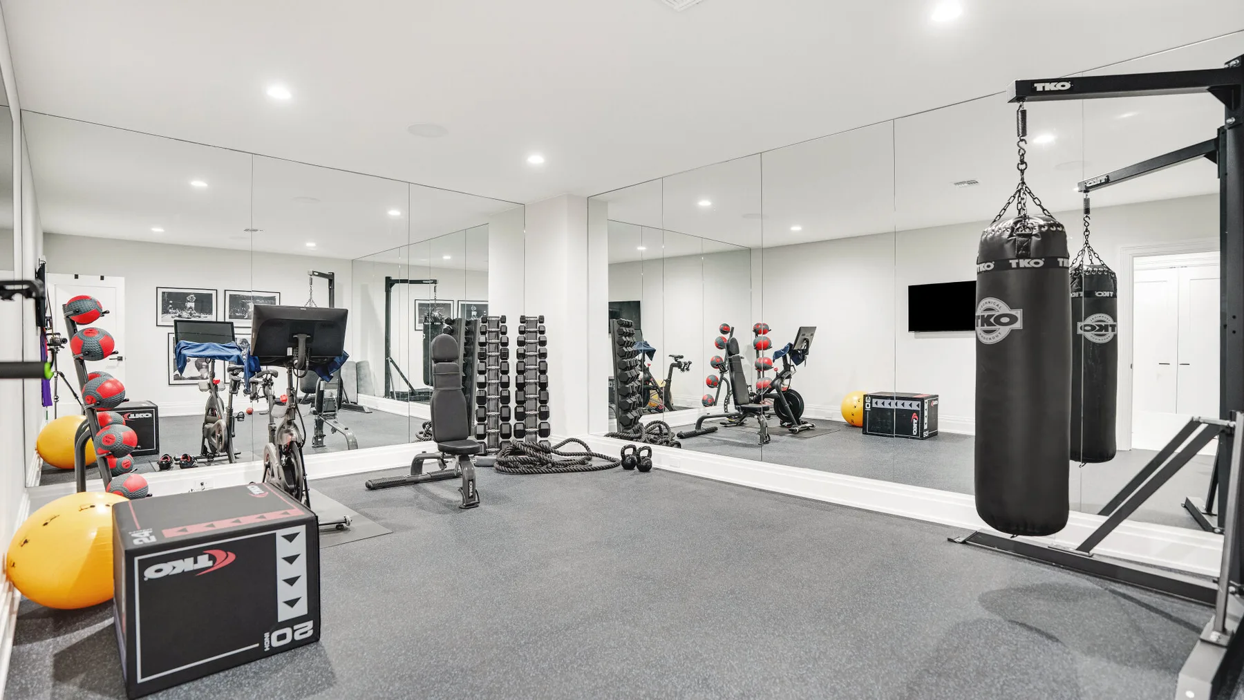 Un gimnasio con espejos, equipo de ejercicio, pesas y un saco de boxeo colgante.