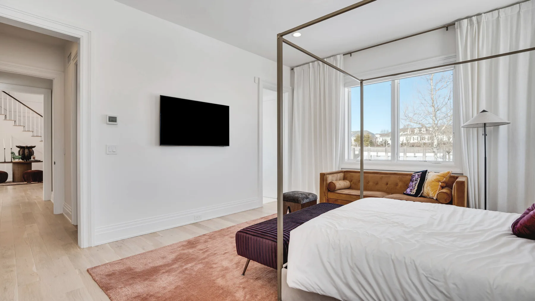 Un dormitorio luminoso con una cama, una zona de estar y grandes ventanas.