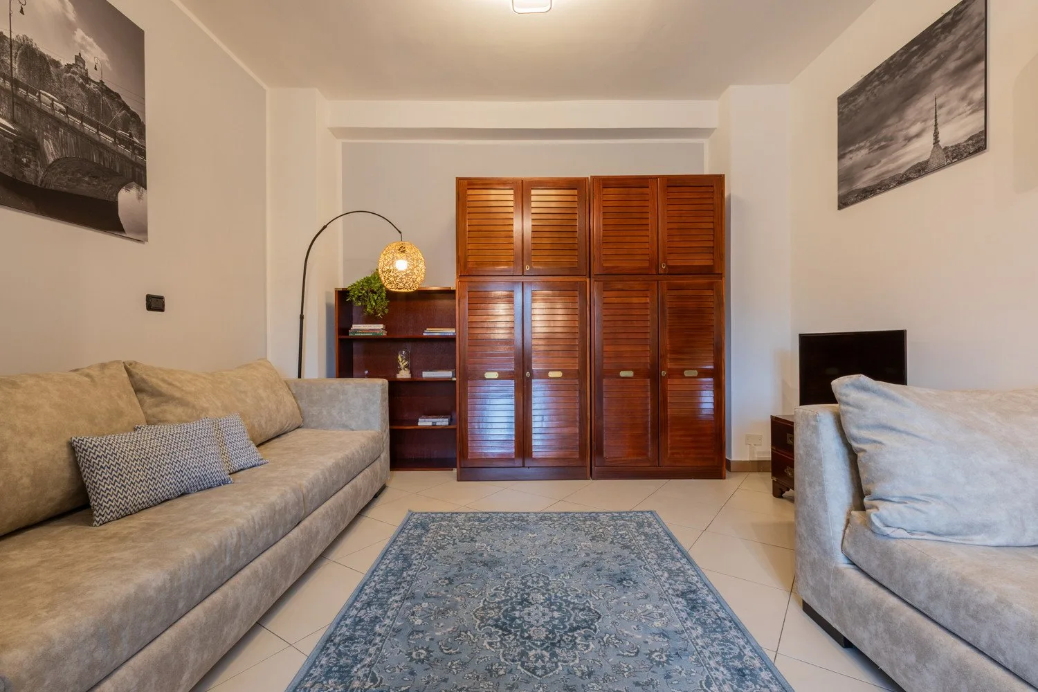 Una sala de estar con asientos, una alfombra estampada y armarios de madera.
