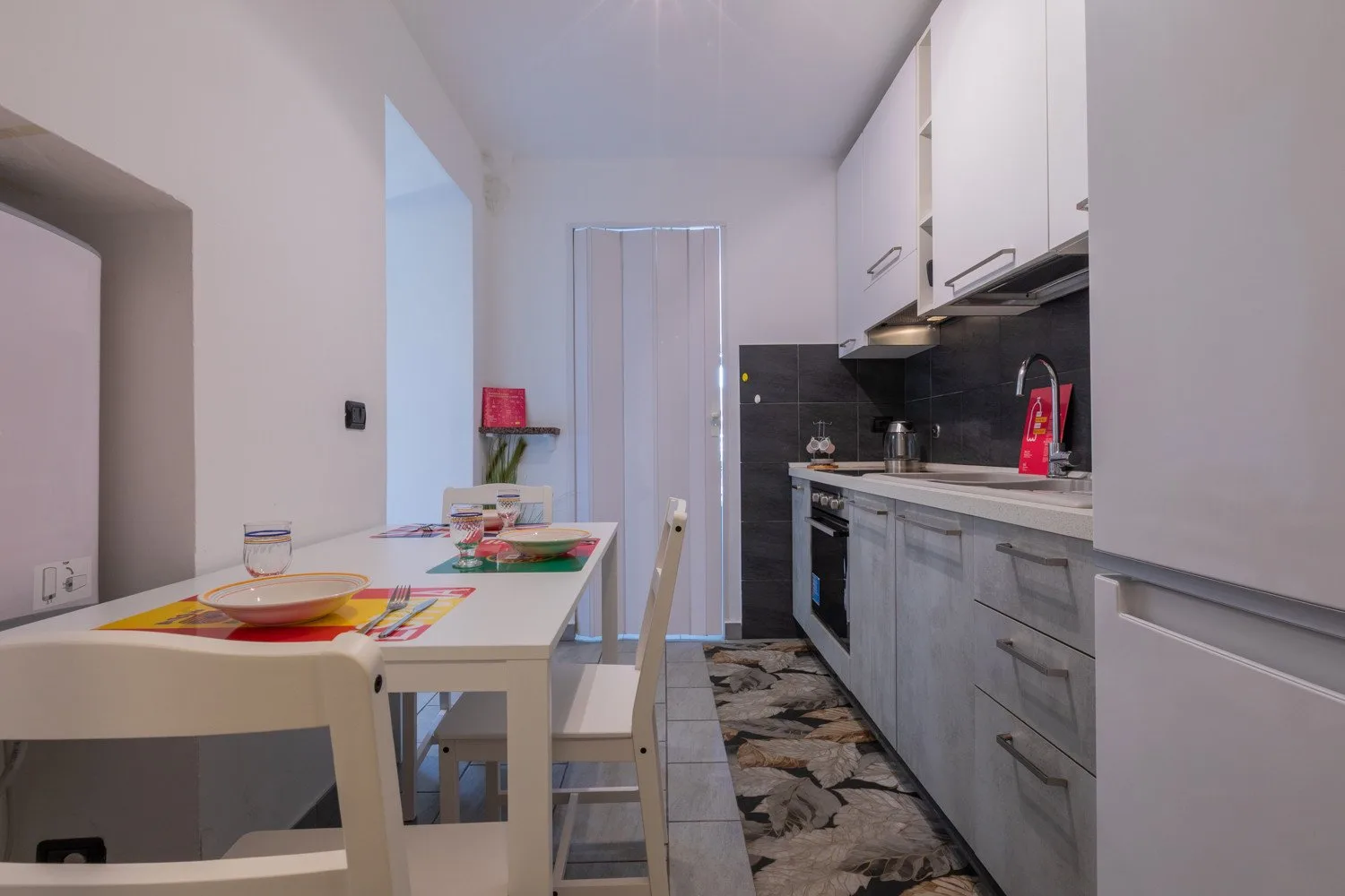 Una cocina estrecha con zona de comedor y una mesa junto a los armarios.