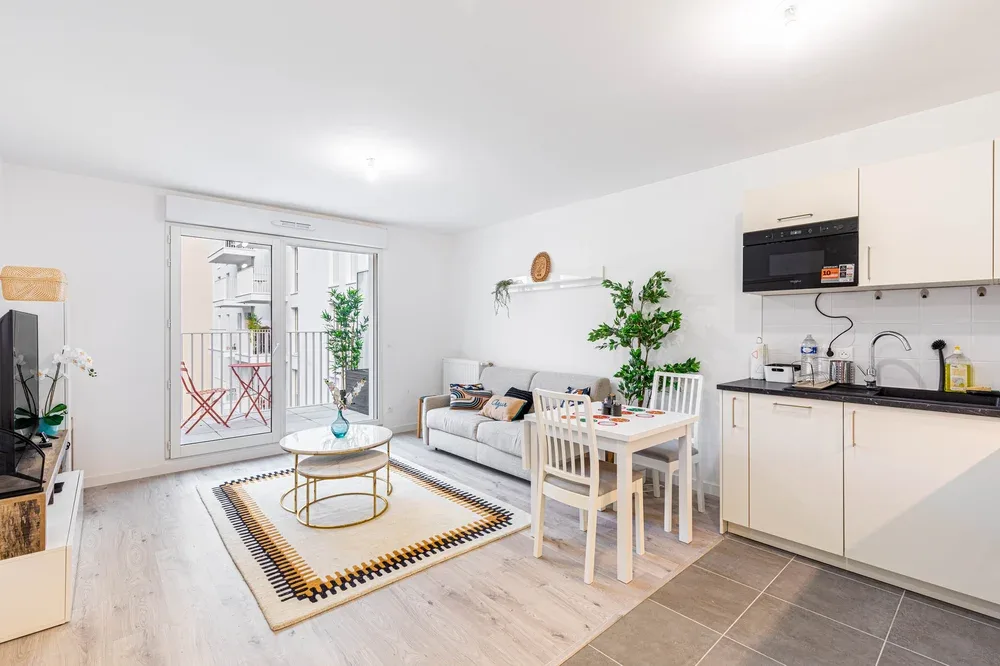 Una luminosa sala-comedor de concepto abierto, con cocina compacta y puertas al balcón.