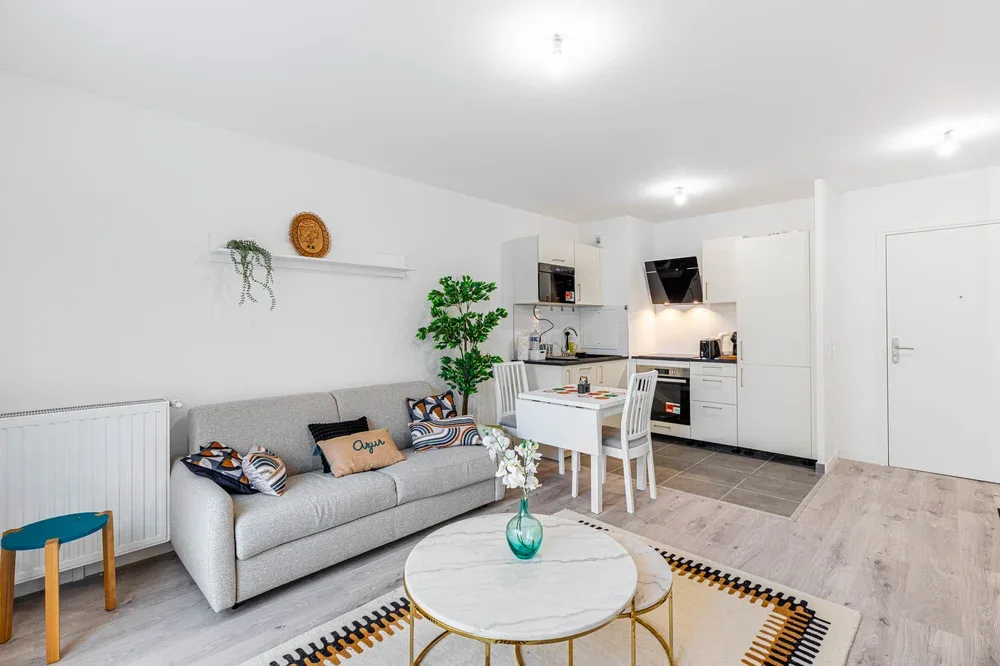 A bright living room with seating, a coffee table, and an open kitchen.