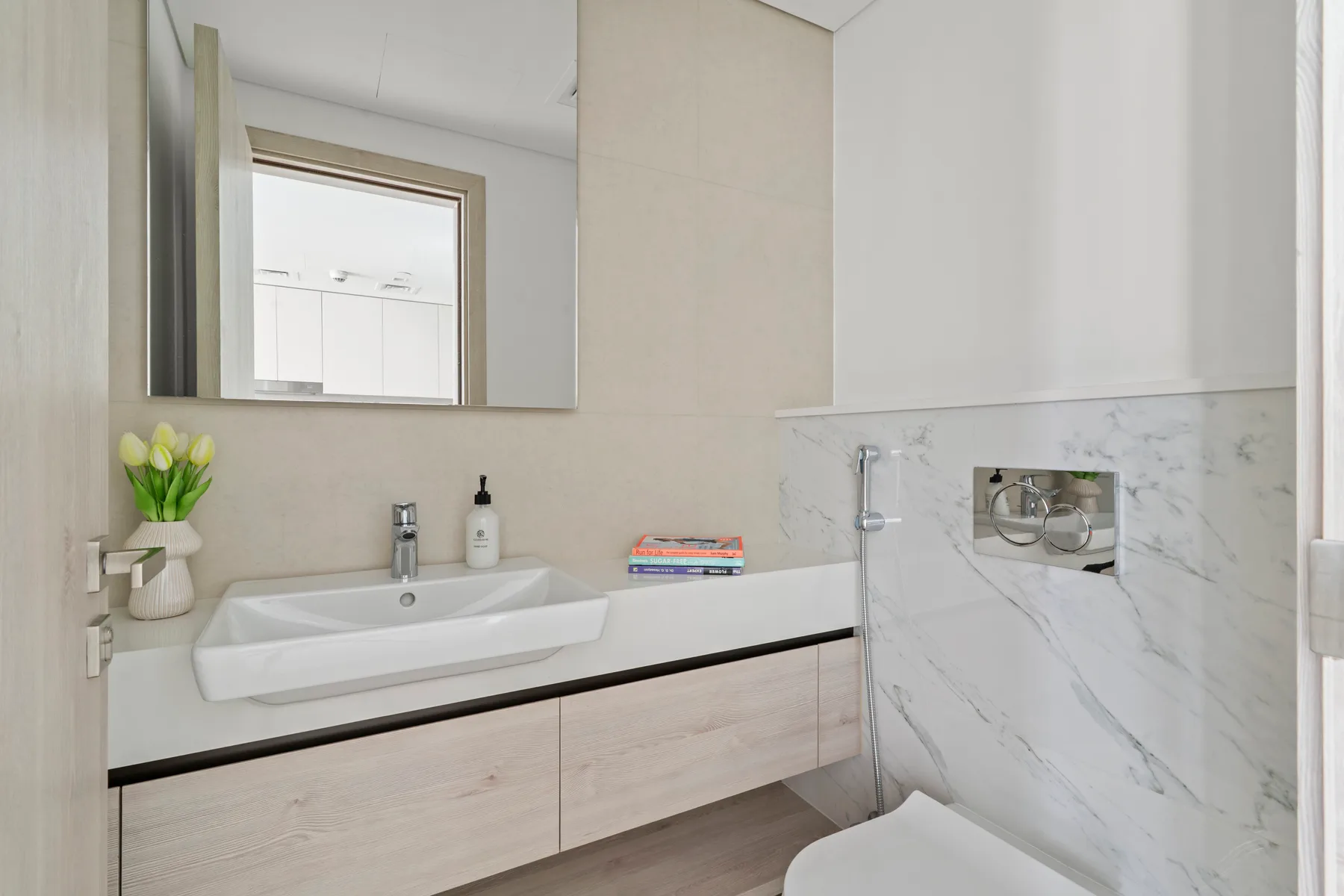 A modern bathroom with a wall-mounted sink, mirror, and shower.