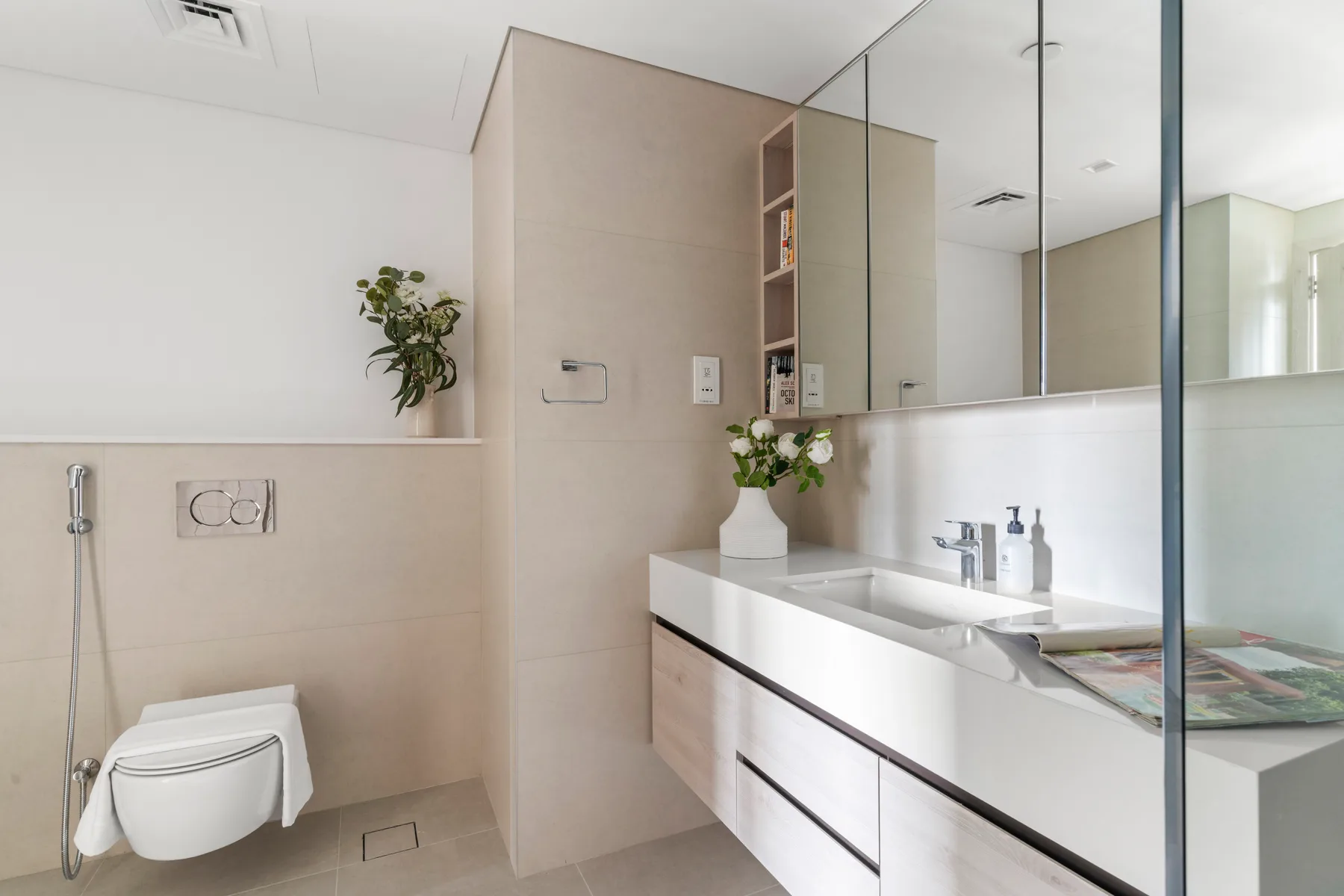A modern bathroom with a long vanity, mirror, and glass shower partition.