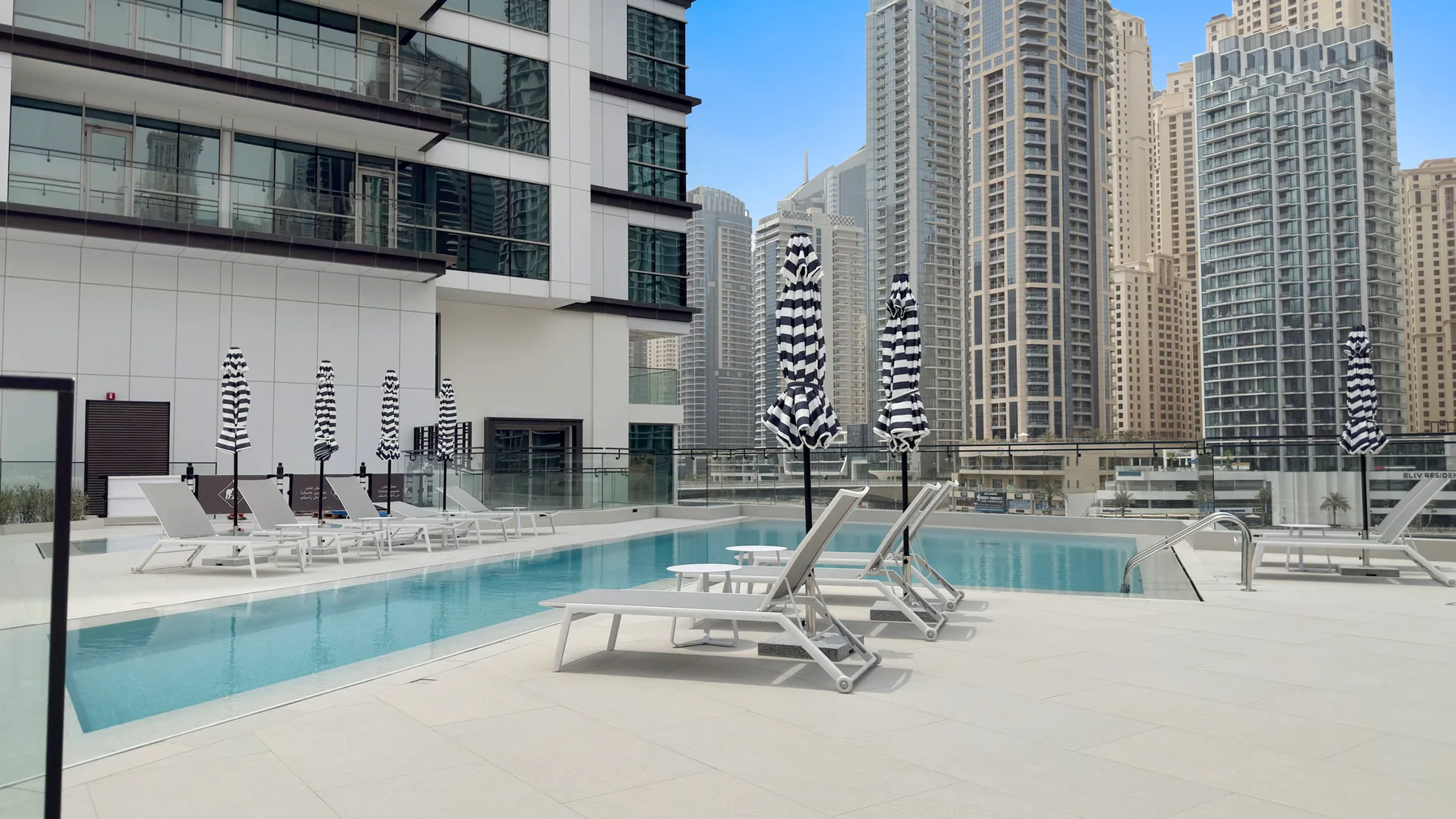 A rooftop pool deck with lounge seating and high-rise buildings in the background.