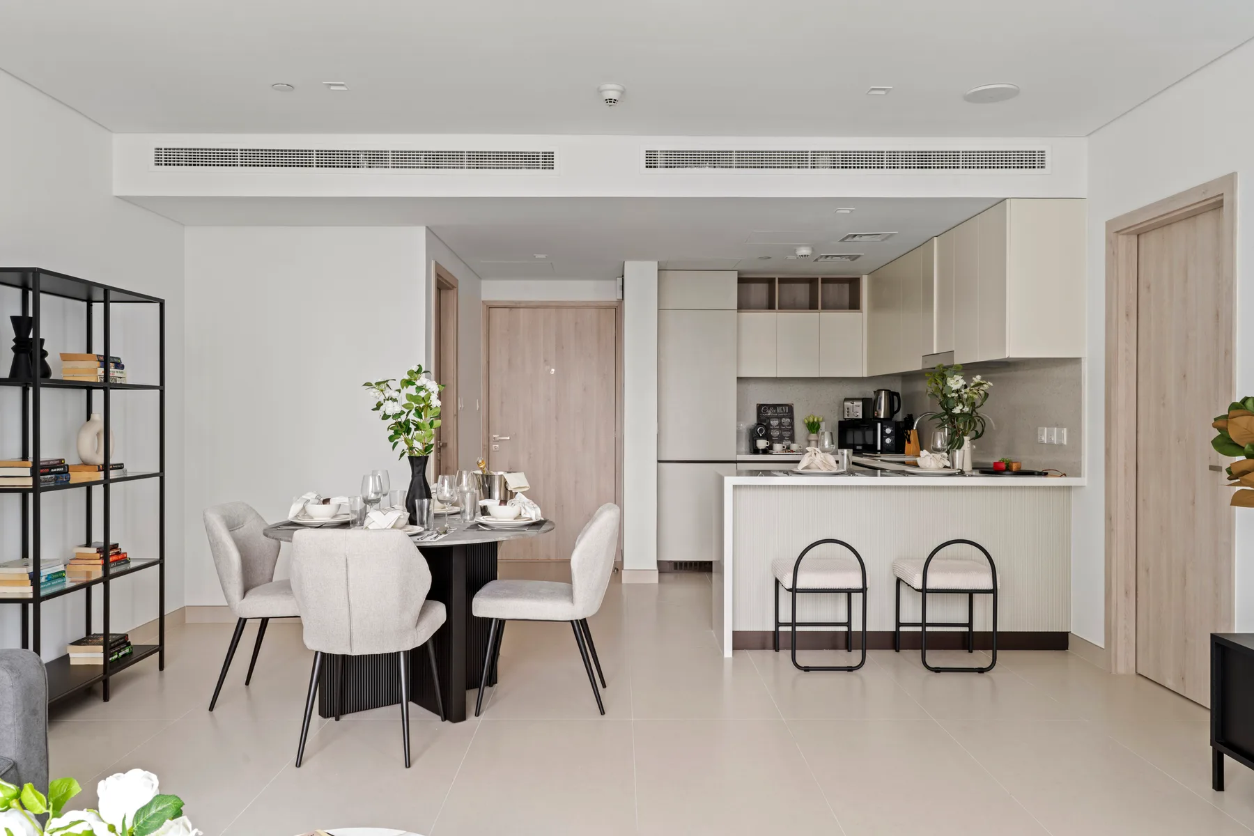 A bright dining area opens onto a kitchen with a counter and stools.