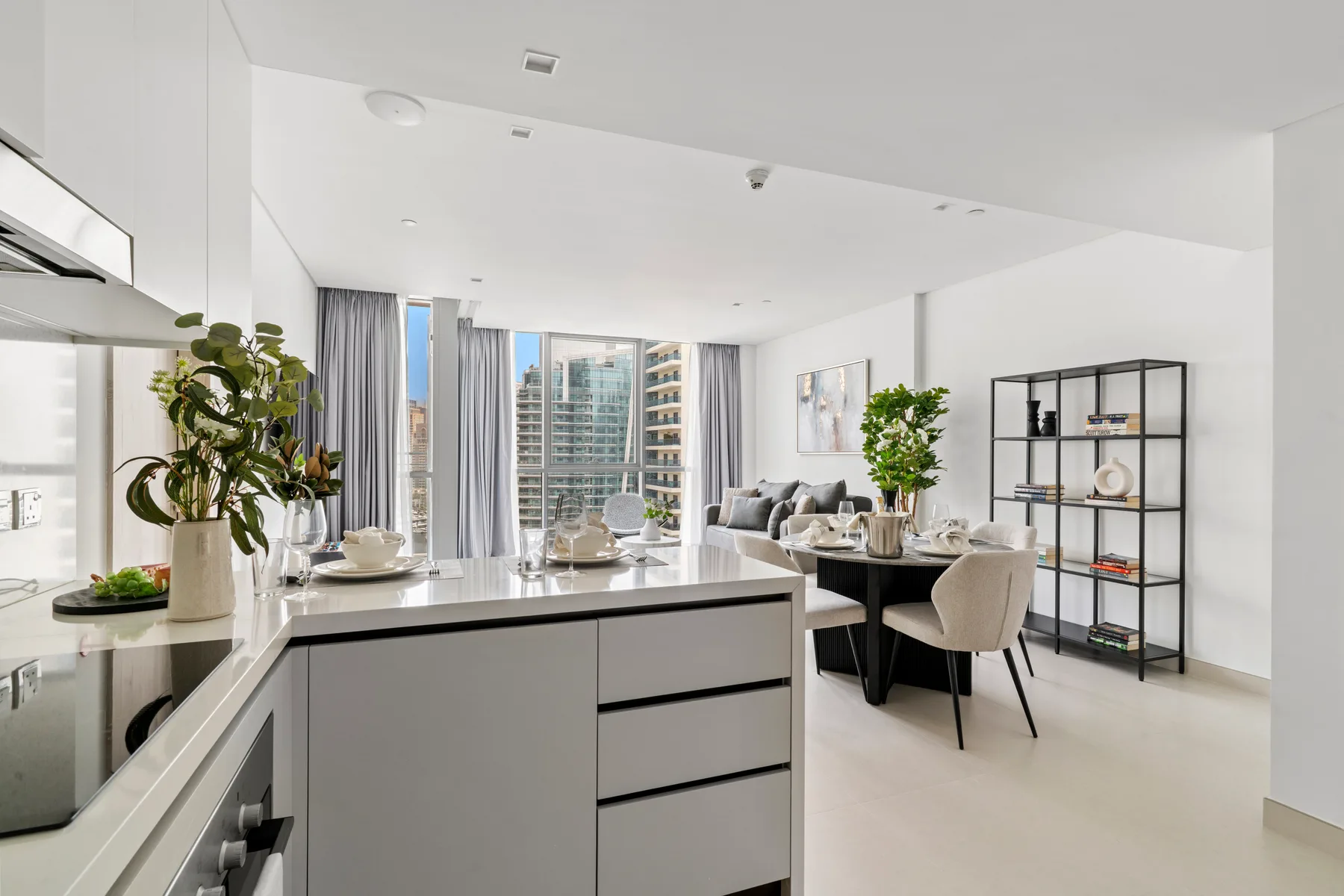 An open-plan kitchen and dining area with a counter and table by large windows.