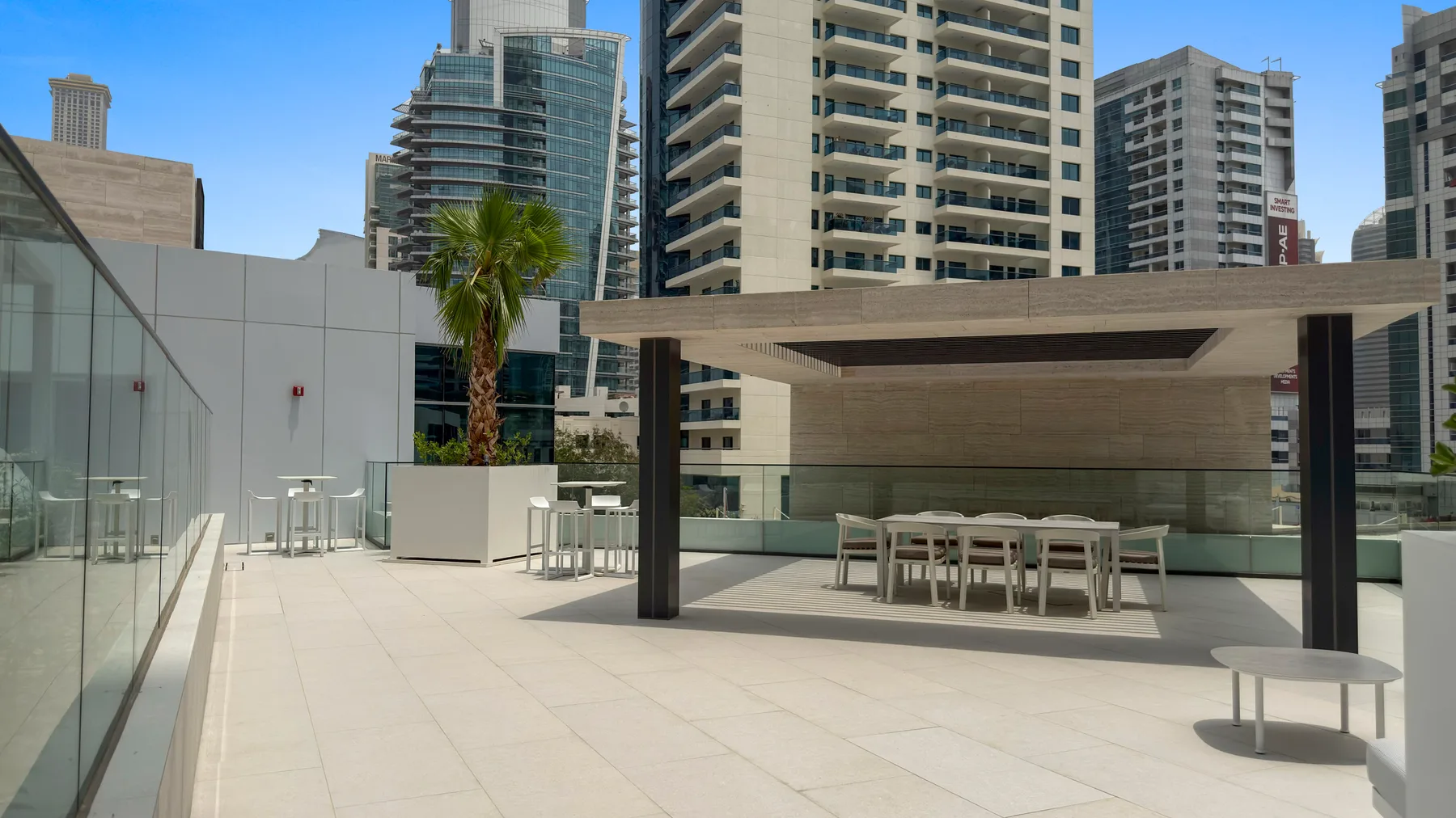 An outdoor terrace with a long table, seating, and surrounding high-rise buildings.