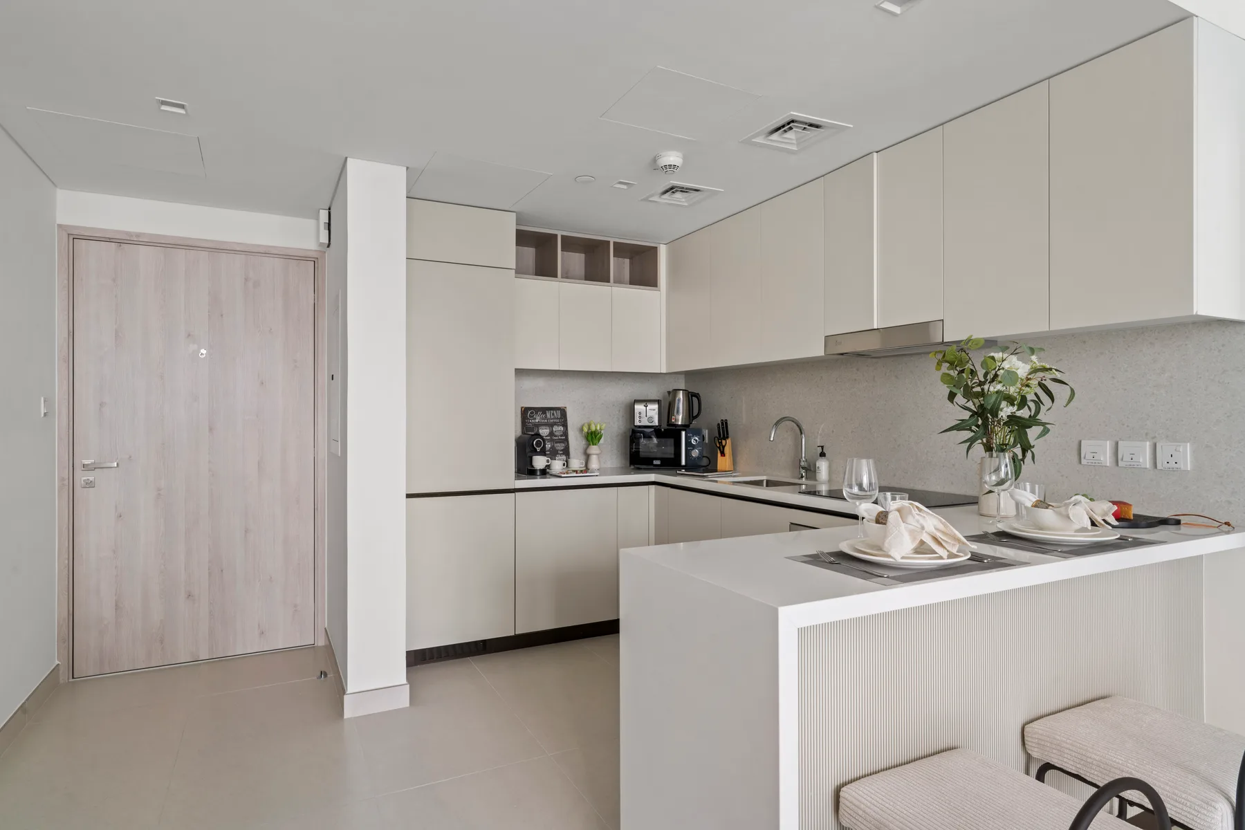 A modern kitchen with pale cabinetry, a countertop, and a dining island.