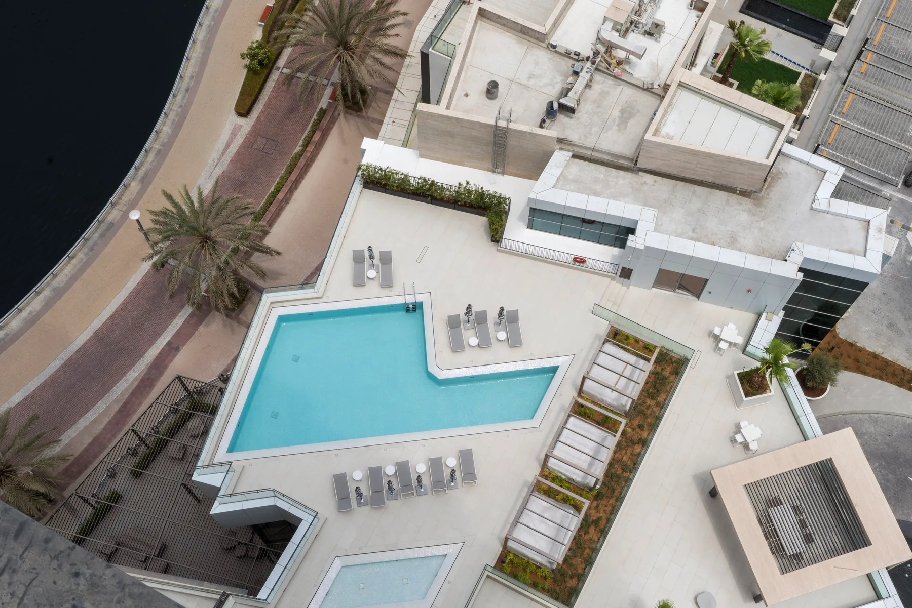 An aerial view of a rooftop pool surrounded by a paved deck and seating.