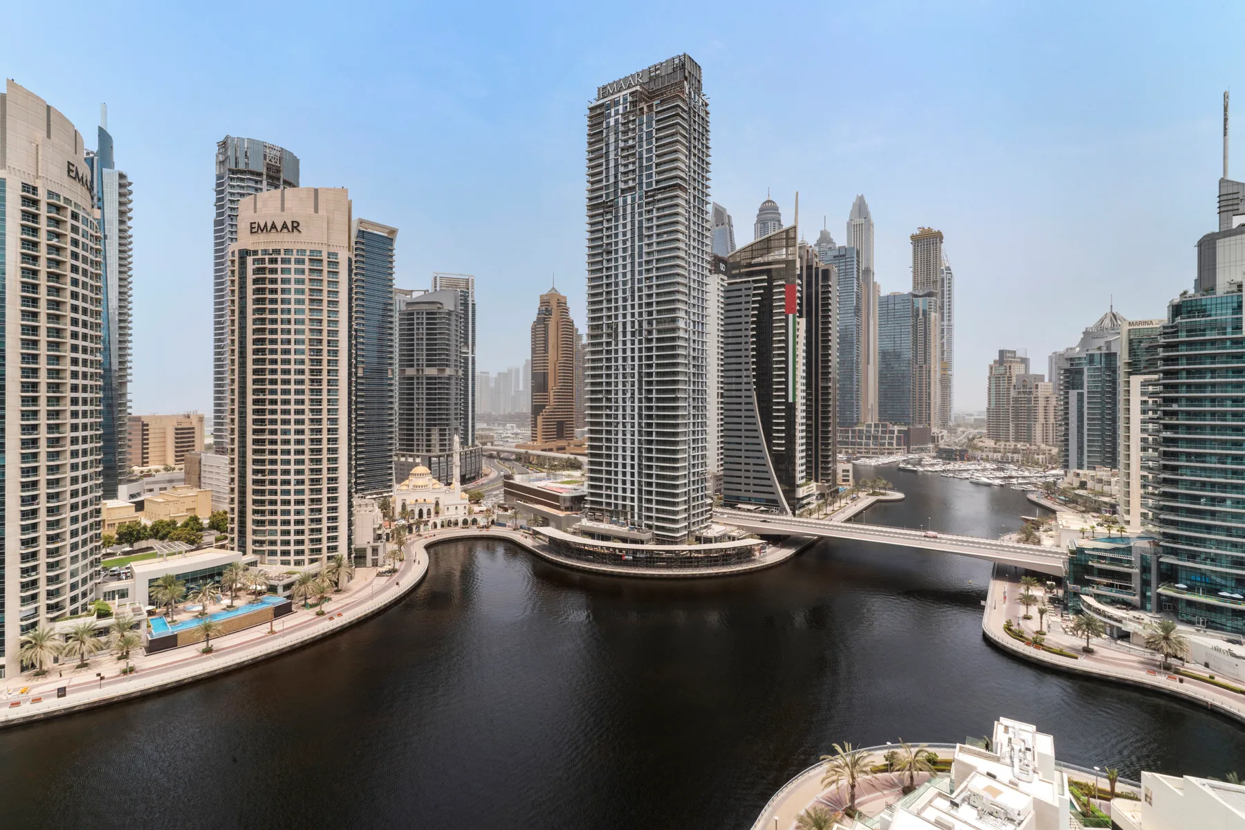 A city skyline of high-rise buildings surrounds a curving waterfront canal.