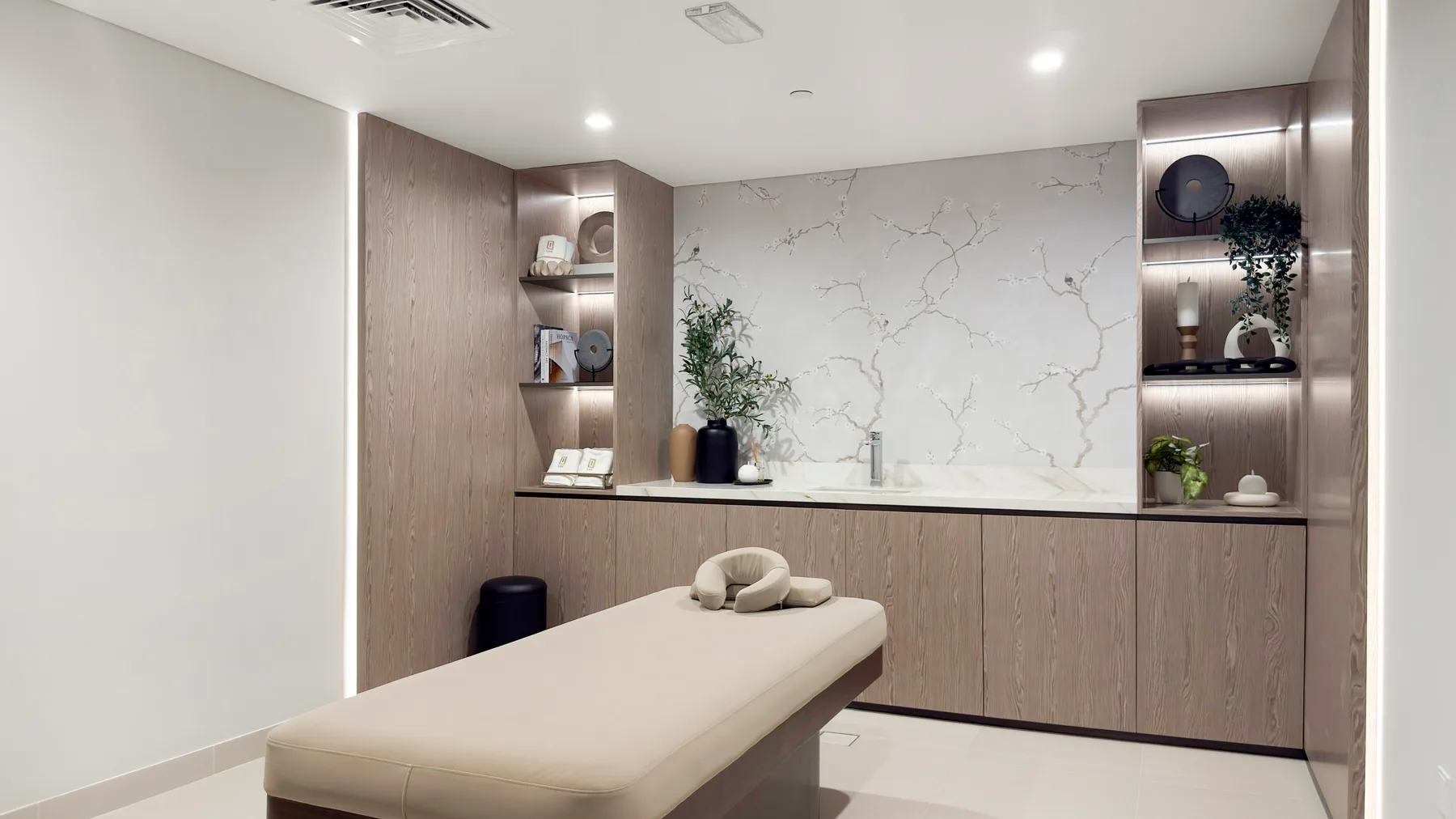 A treatment room with a padded table and a counter against a marble-patterned wall.