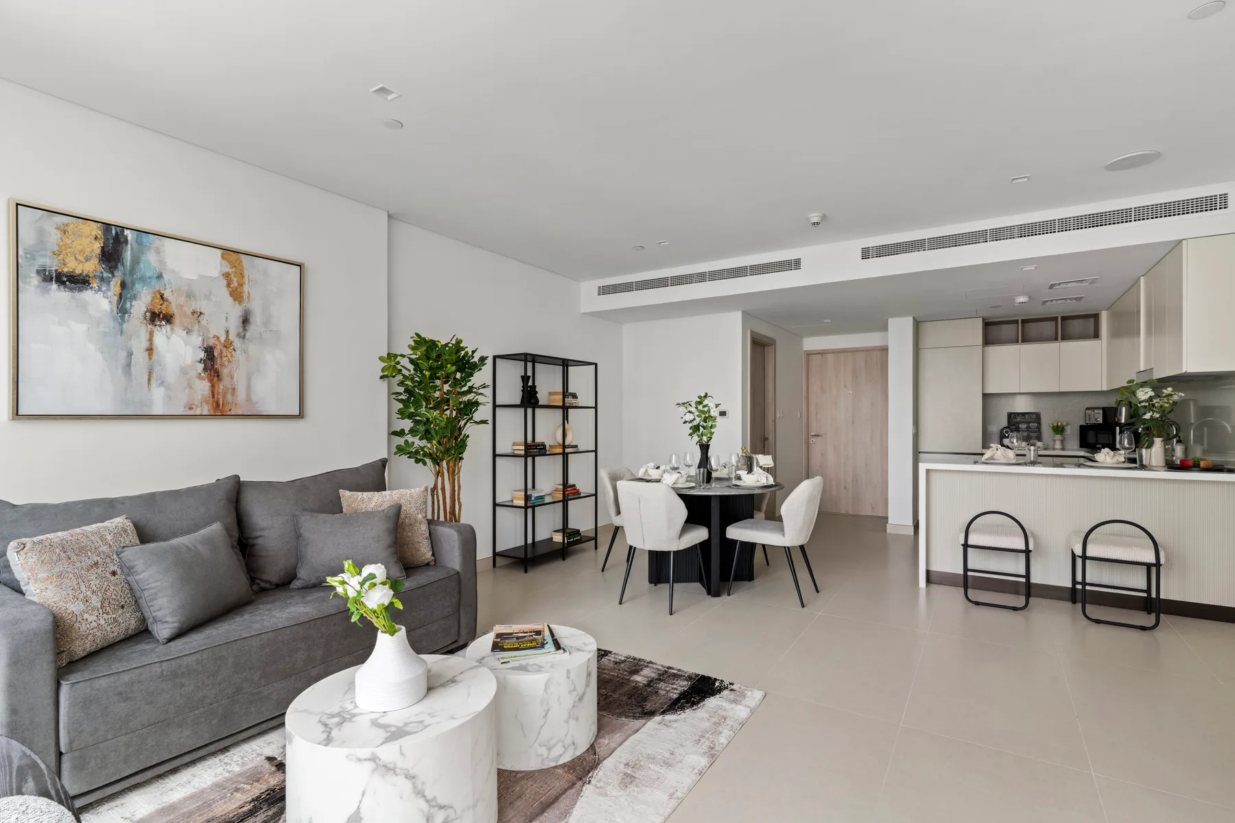 Una sala-comedor moderna con asientos grises y una barra de cocina.